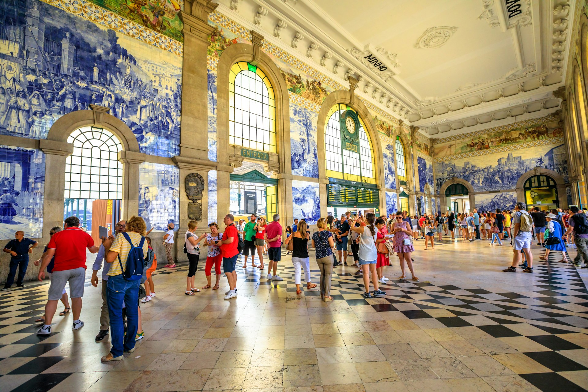 Tourists mill around in a station concourse admiring its intricately tiled walls