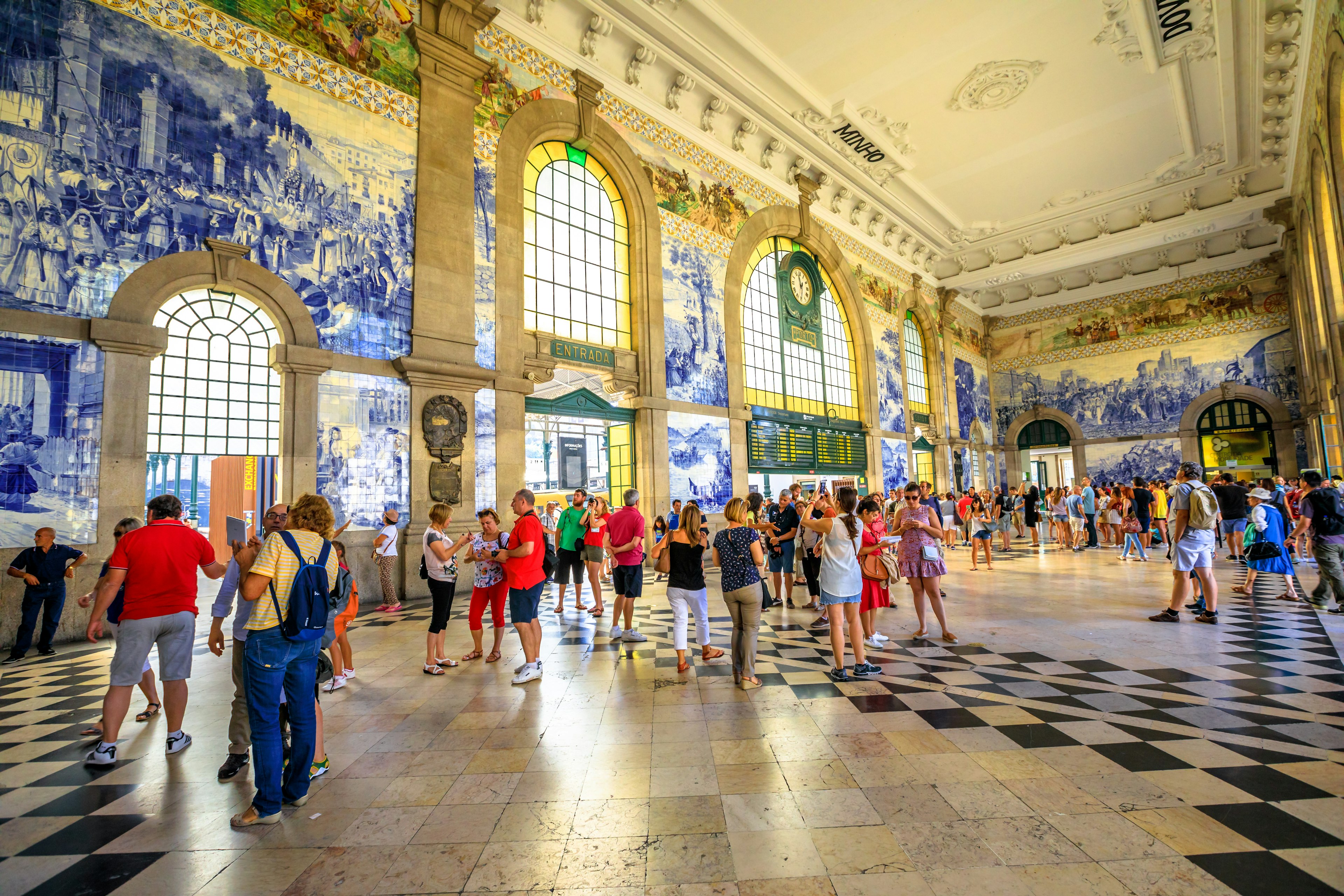 Tourists mill around in a station concourse admiring its intricately tiled walls