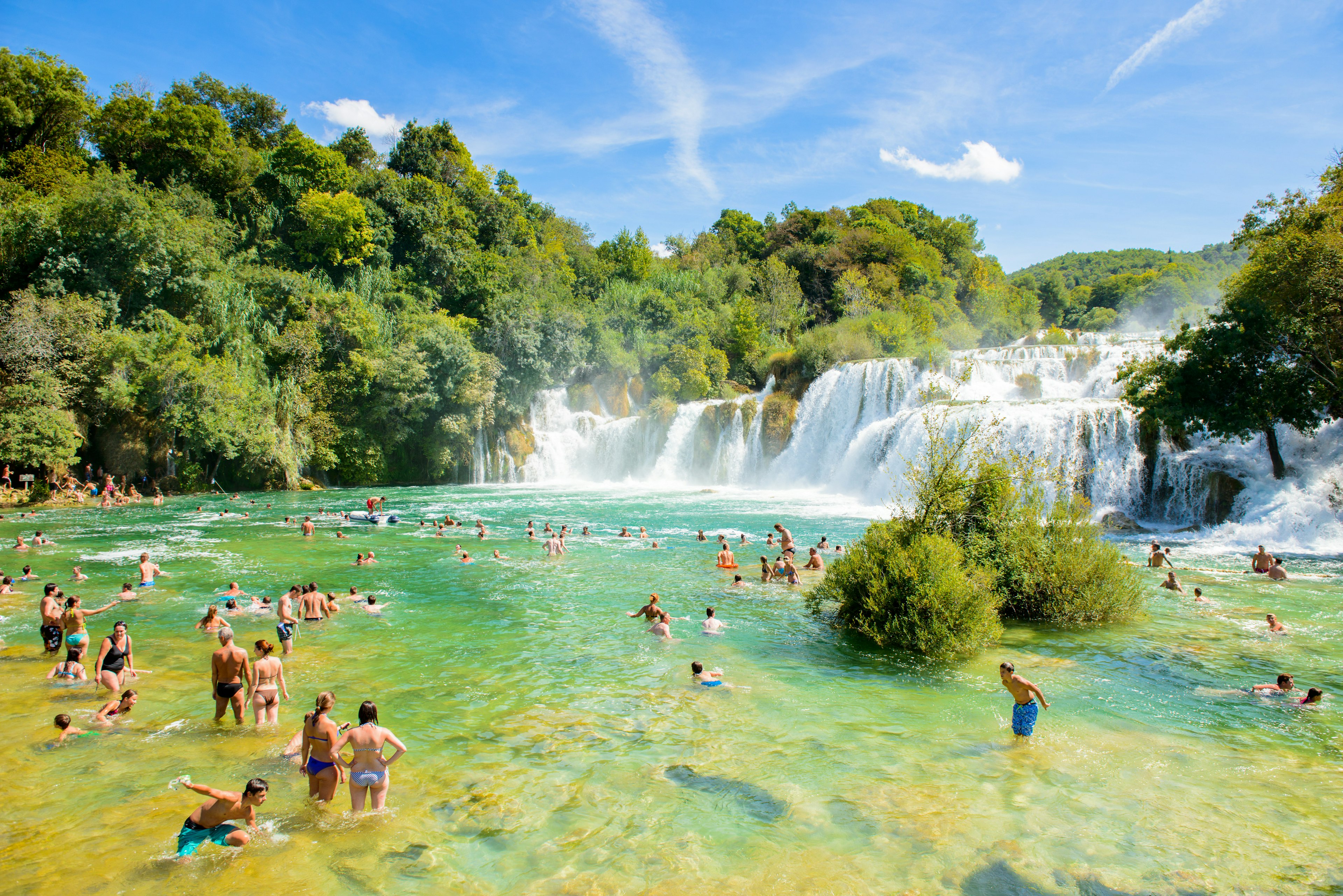 People swimming in pools fed by waterfalls