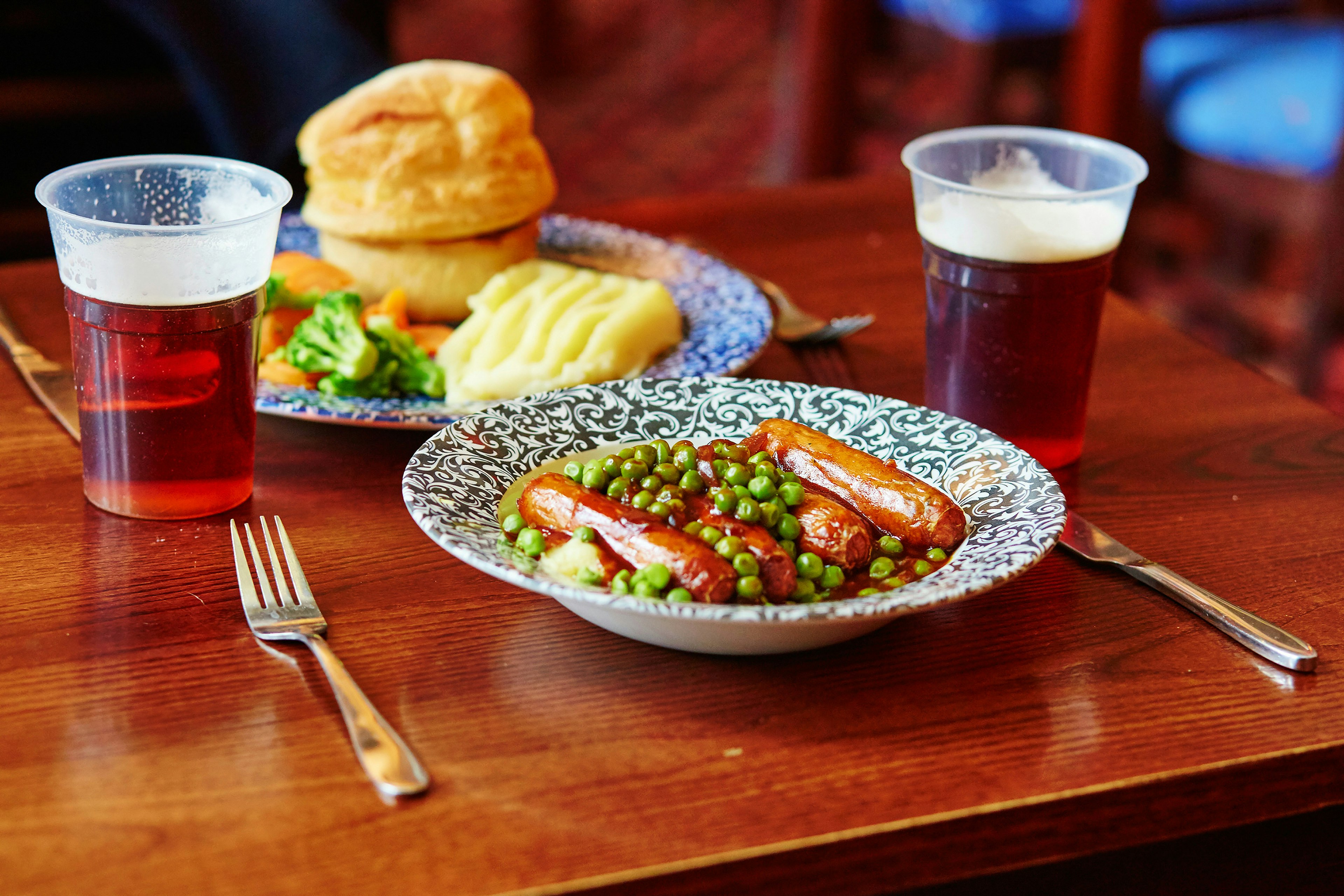 Pork sausages, mashed potatoes, green peas and onion gravy with ale in a traditional English pub