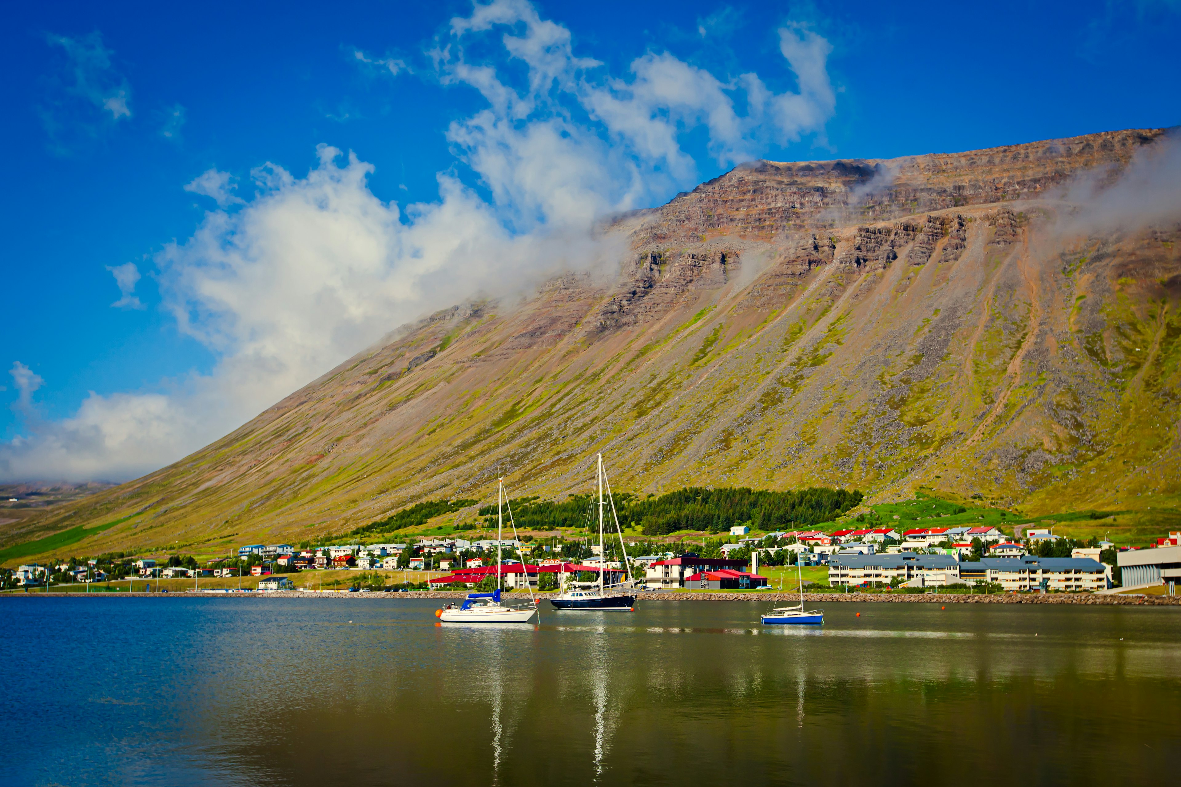 Houses at the foot of a mountain that reaches all the way down to the coastline