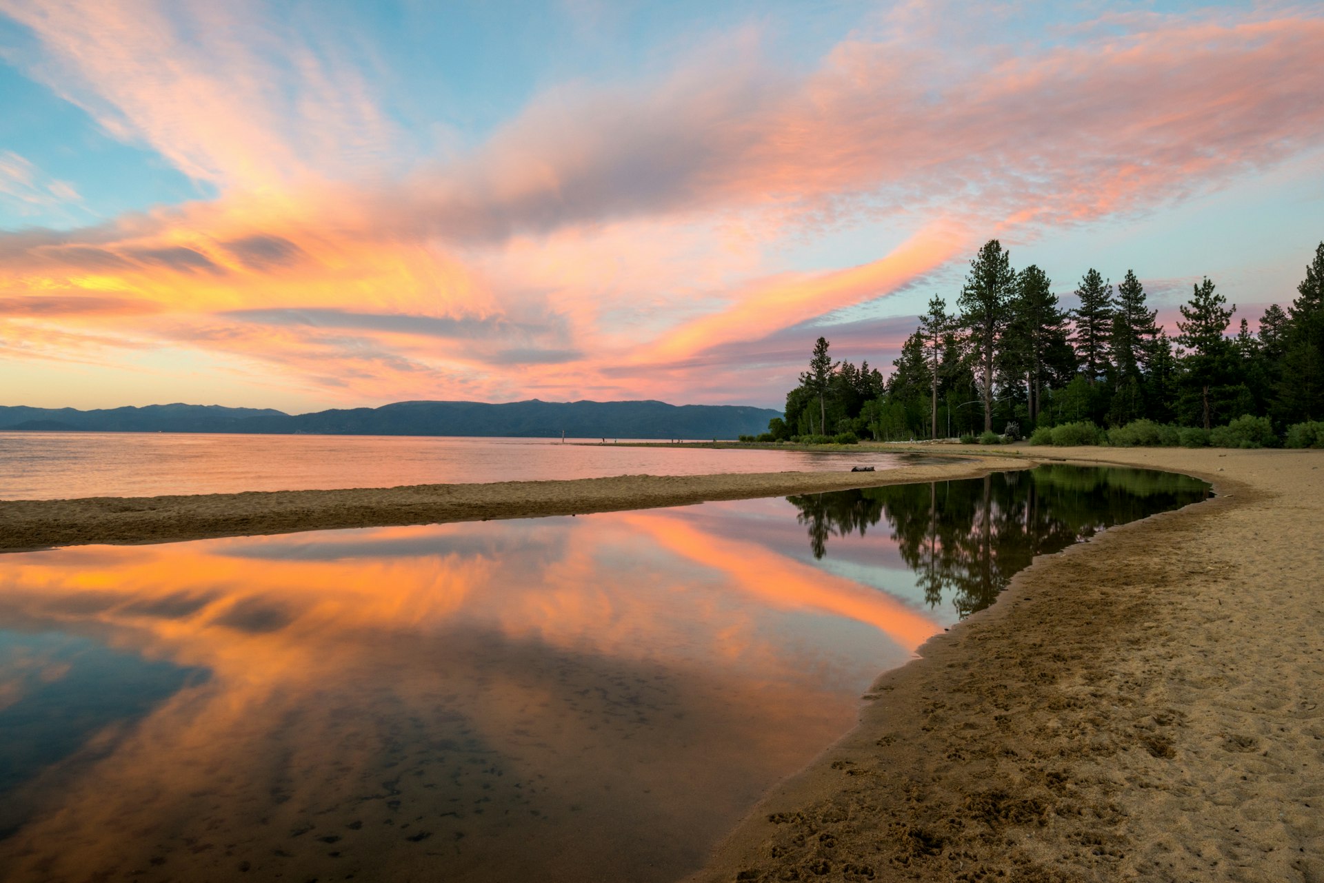 A gorgeous sunset reflects off of Lake Tahoe at Kiva Beach in the summer near South Lake Tahoe, California