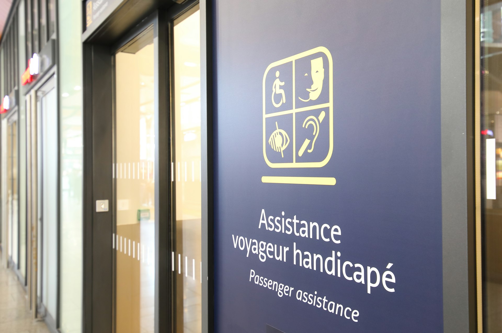 A sign reading "Assistance voyageur handicapé (Passenger assistance)" on the door of an office at a train station in Paris, France