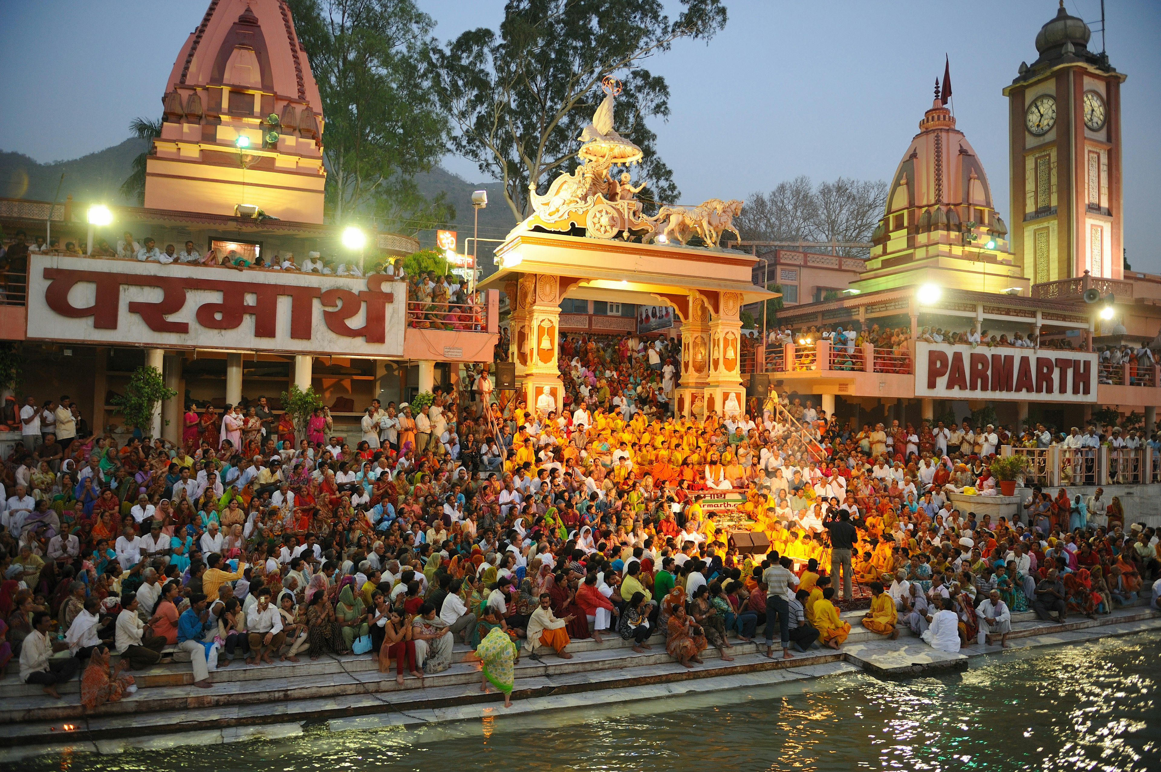 People sit on steps that lead down to the riverside