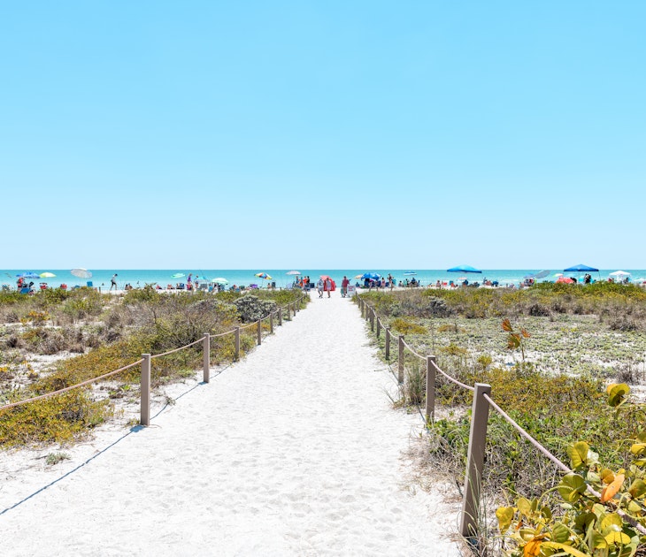Bowman's beach at Sanibel Island with sandy trail, path, walkway, fence, many people, crowd in distance, crowded coast, coastline shelling, looking for shells
1163242073