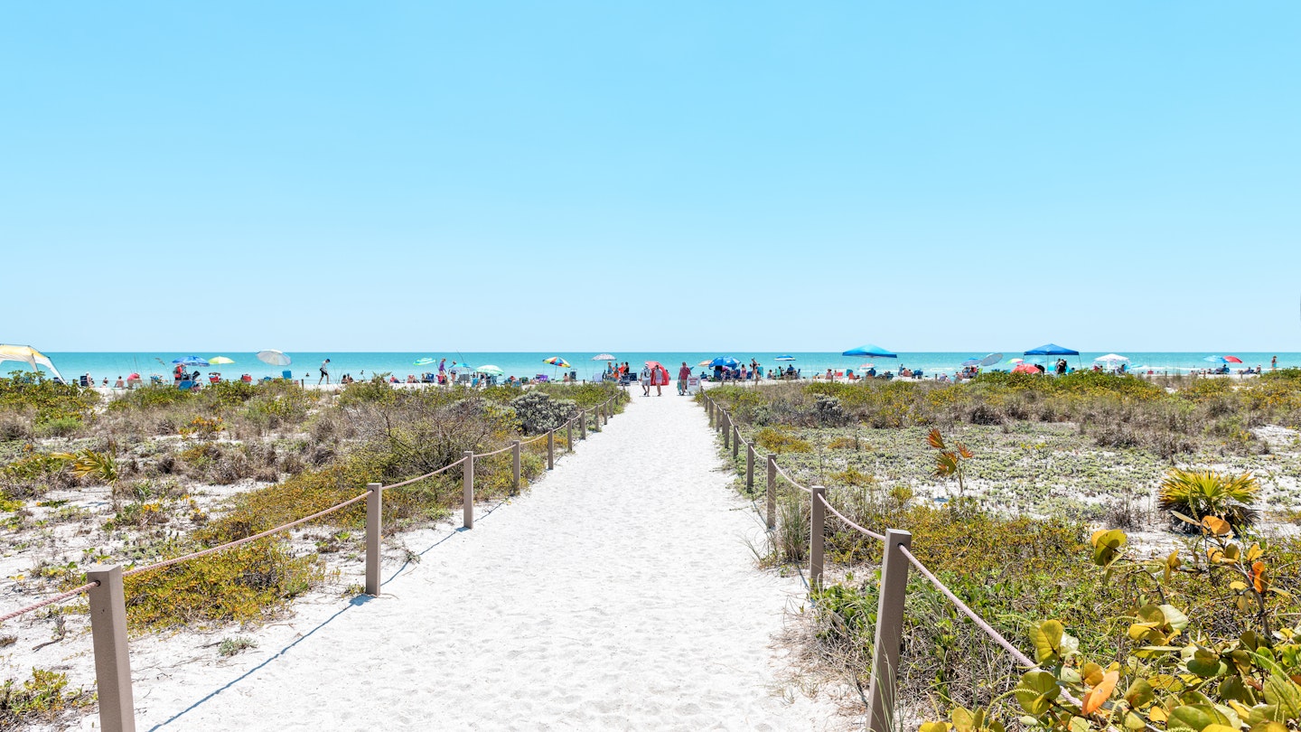 Bowman's beach at Sanibel Island with sandy trail, path, walkway, fence, many people, crowd in distance, crowded coast, coastline shelling, looking for shells
1163242073