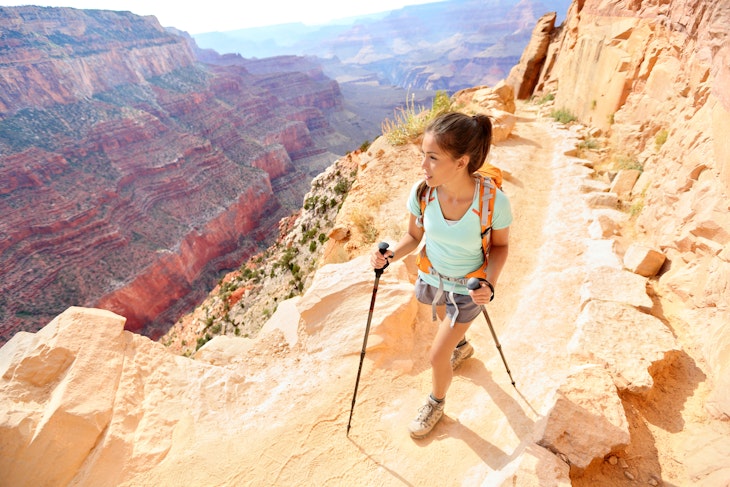 A woman hiking along a ridge in the Grand Canyon using hiking poles