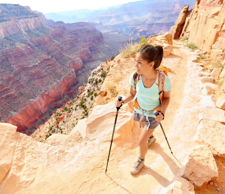 A woman hiking along a ridge in the Grand Canyon using hiking poles