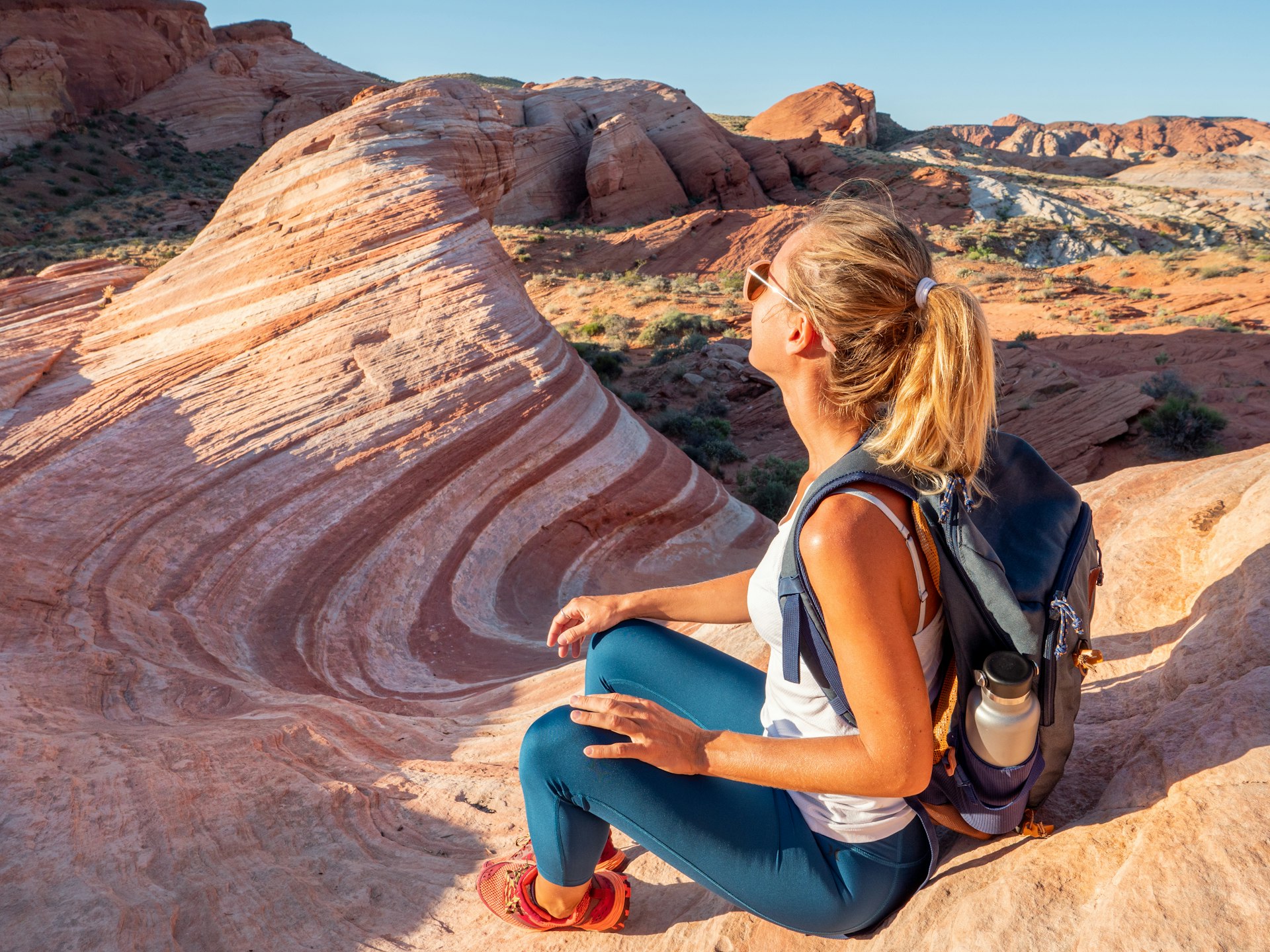 Sporty young woman contemplating wavy bands of red sandstone in Valley of Fire State Park, Nevada, USA