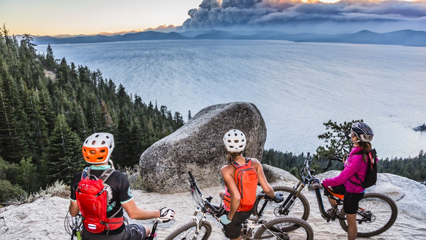 1270702234
Three mountain bikers take a rest on the Flume Trail, beside Lake Tahoe and watch the smoke clouds from the King Fire in the distance.
cloud, elevated view, king fire, mountain biker, non urban scene, purple color, red color, rock, smoke, sportswear, wildfire