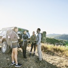 Smiling father and his three daughters standing at the rear of their car before going hiking in Washington State
