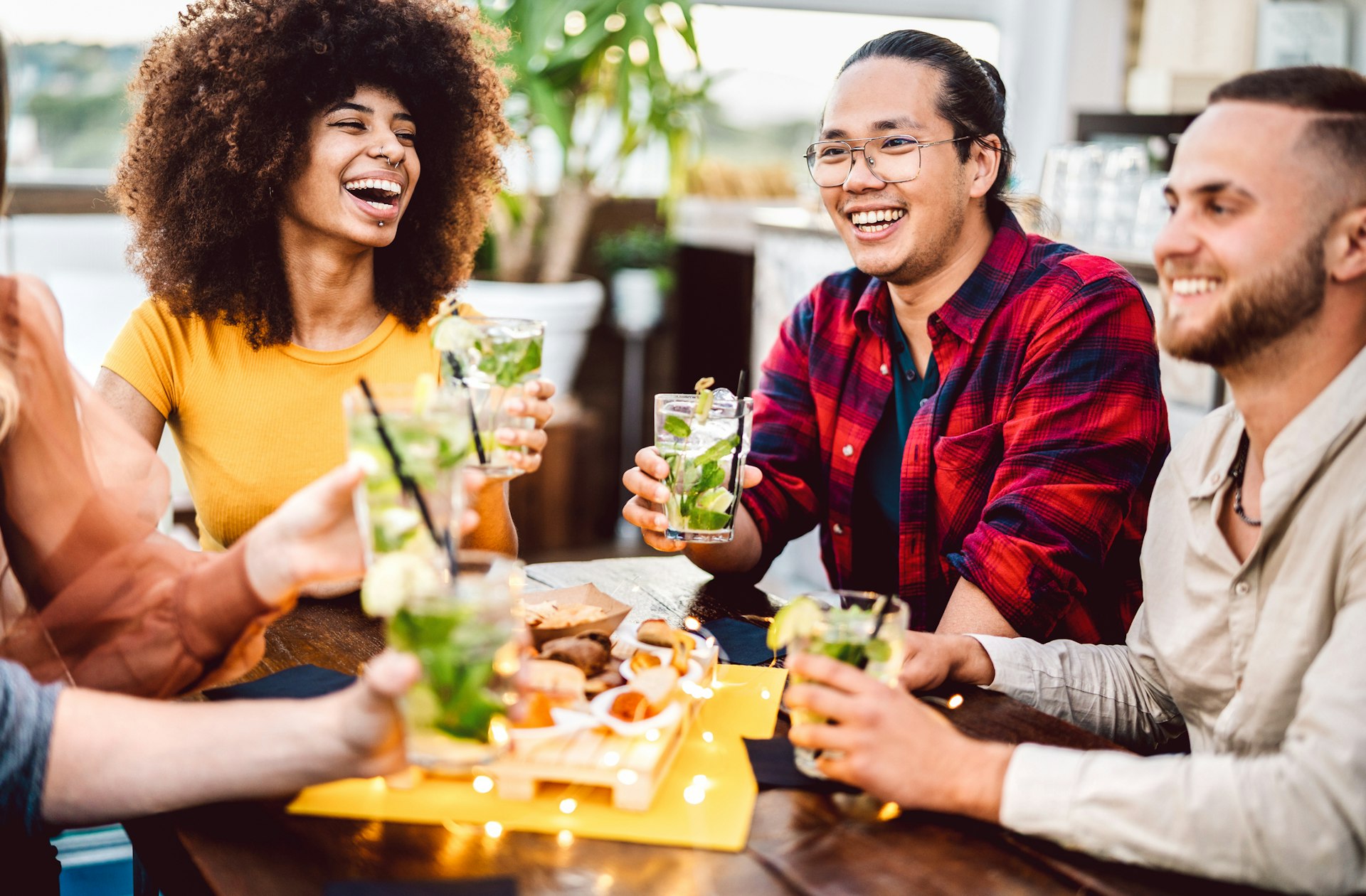A group of friends laughing together as they drink outside in the sun