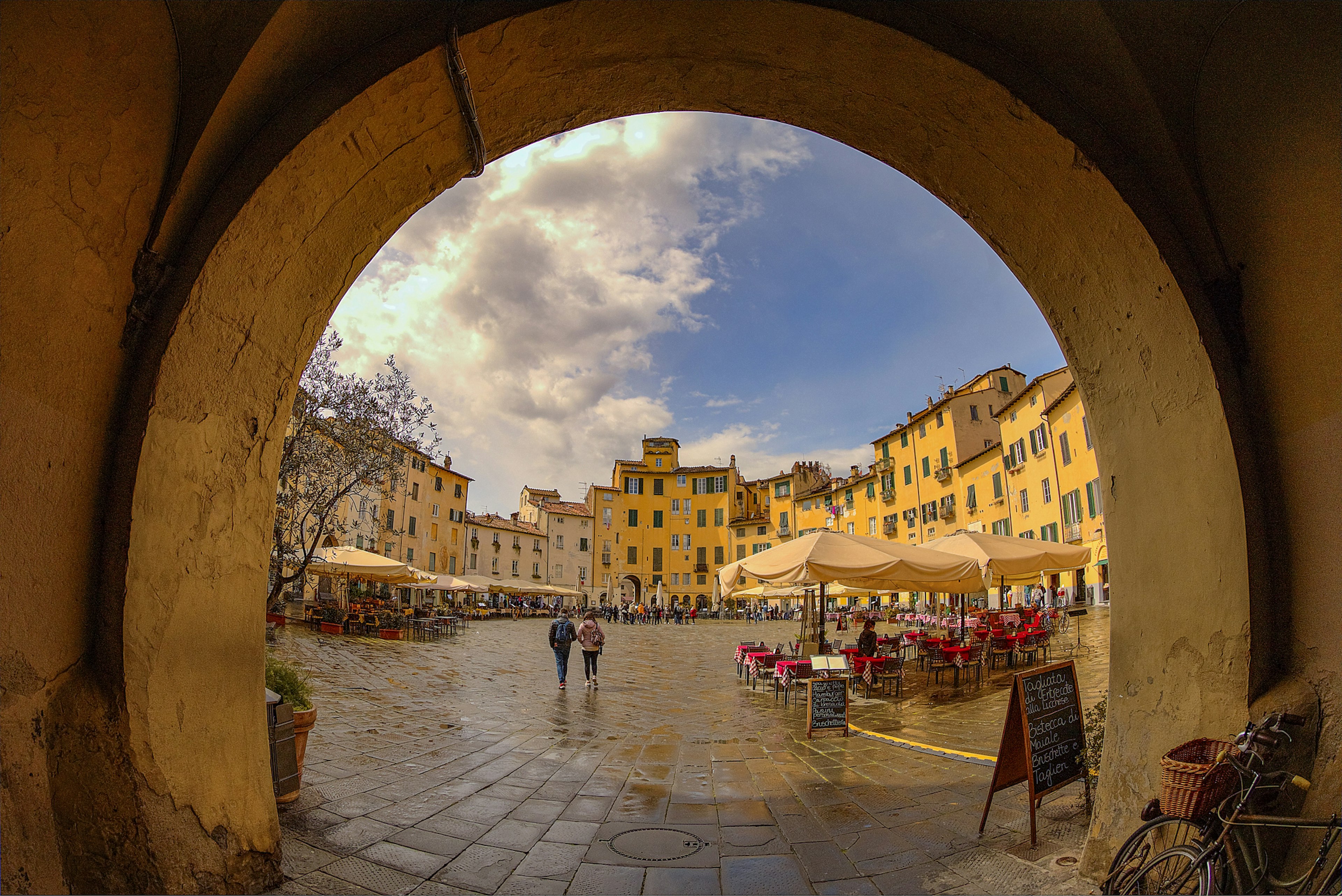 An open elliptical space in a town with tables outside for diners