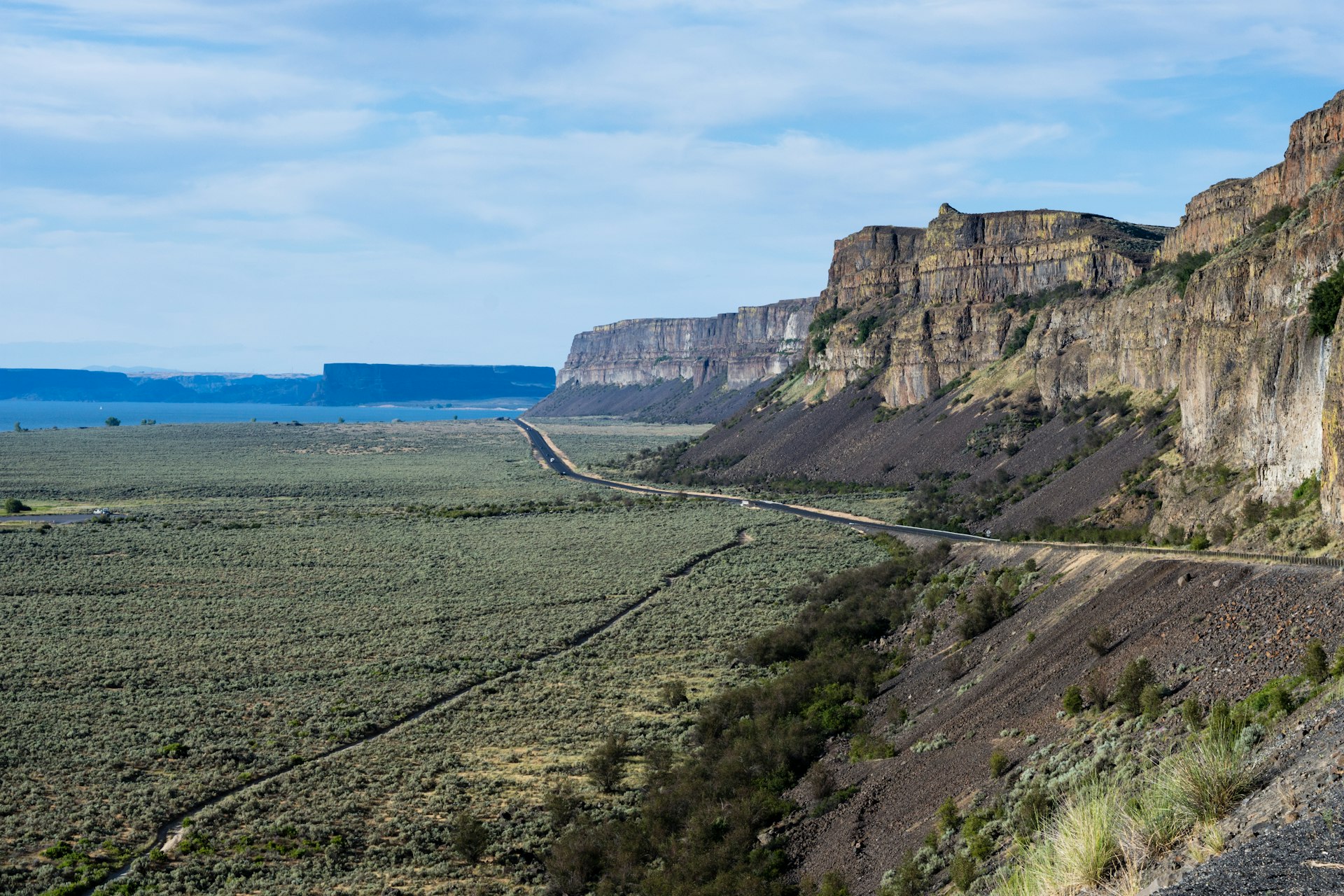 A scenic desert road running along basalt rock formations near Grand Coulee in Eastern Washington State, USA