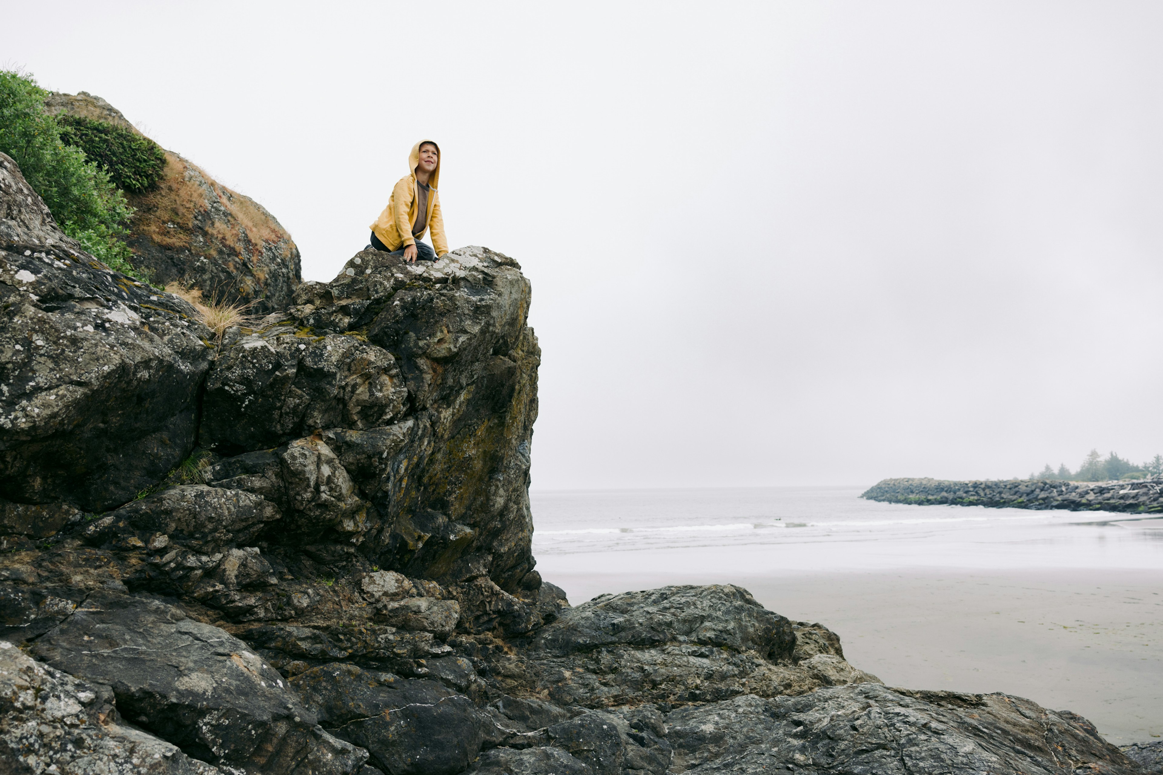 A boy looking at the view from a rocky outcrop in Cape Disappointment Park, WA