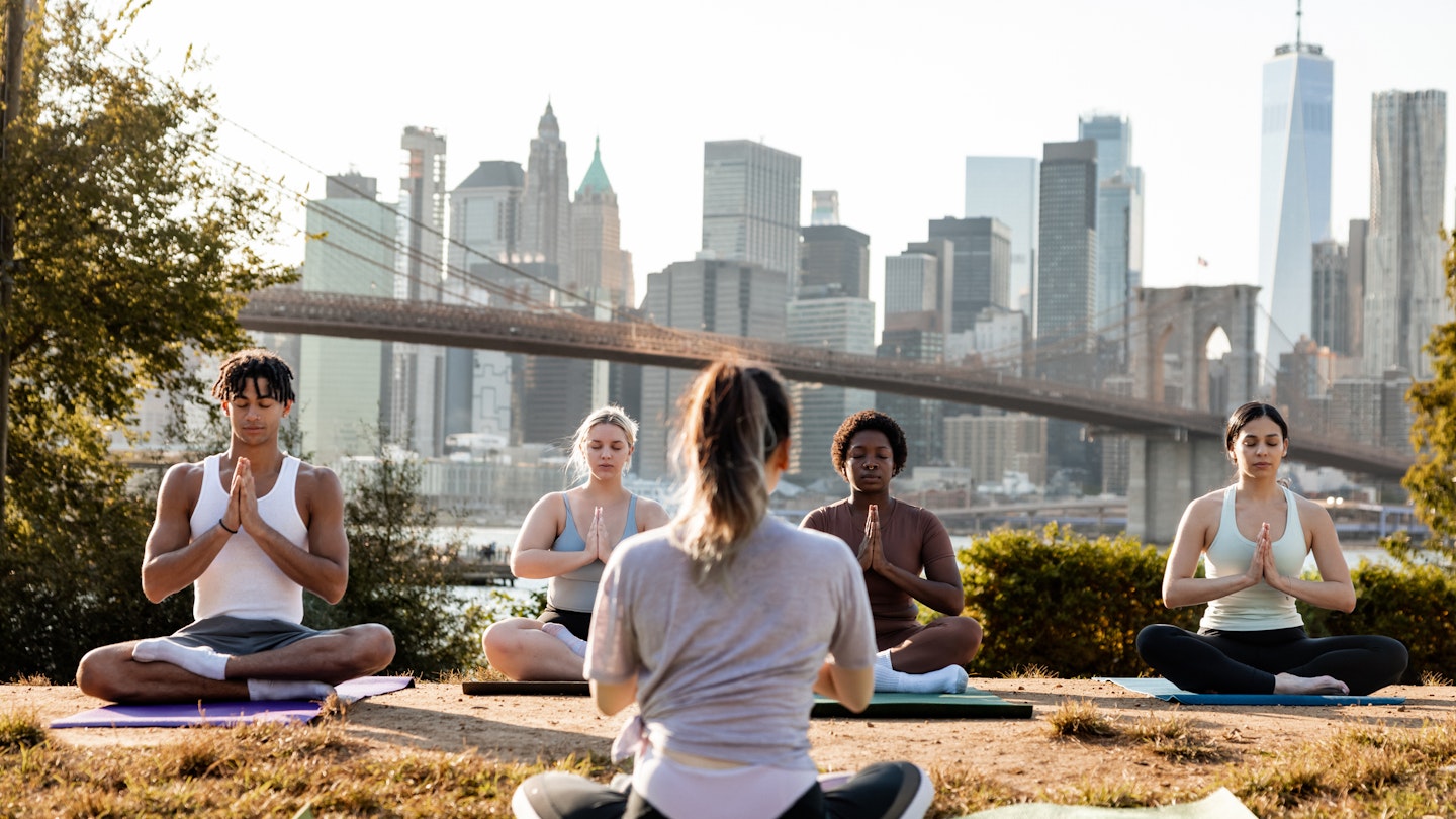 Group of young people attending to a yoga class outdoors at sunset with New York cityscape on their background. They are meditating and relaxing.
1438704047