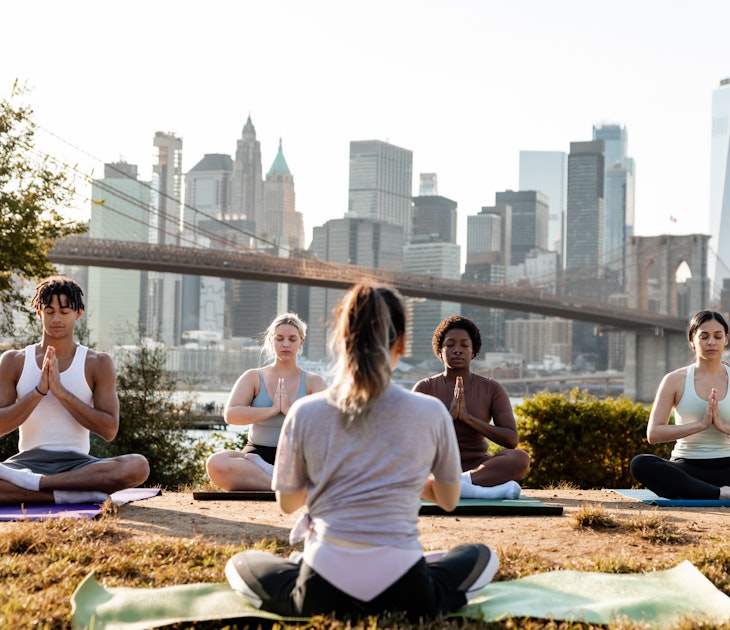 Group of young people attending to a yoga class outdoors at sunset with New York cityscape on their background. They are meditating and relaxing.
1438704047