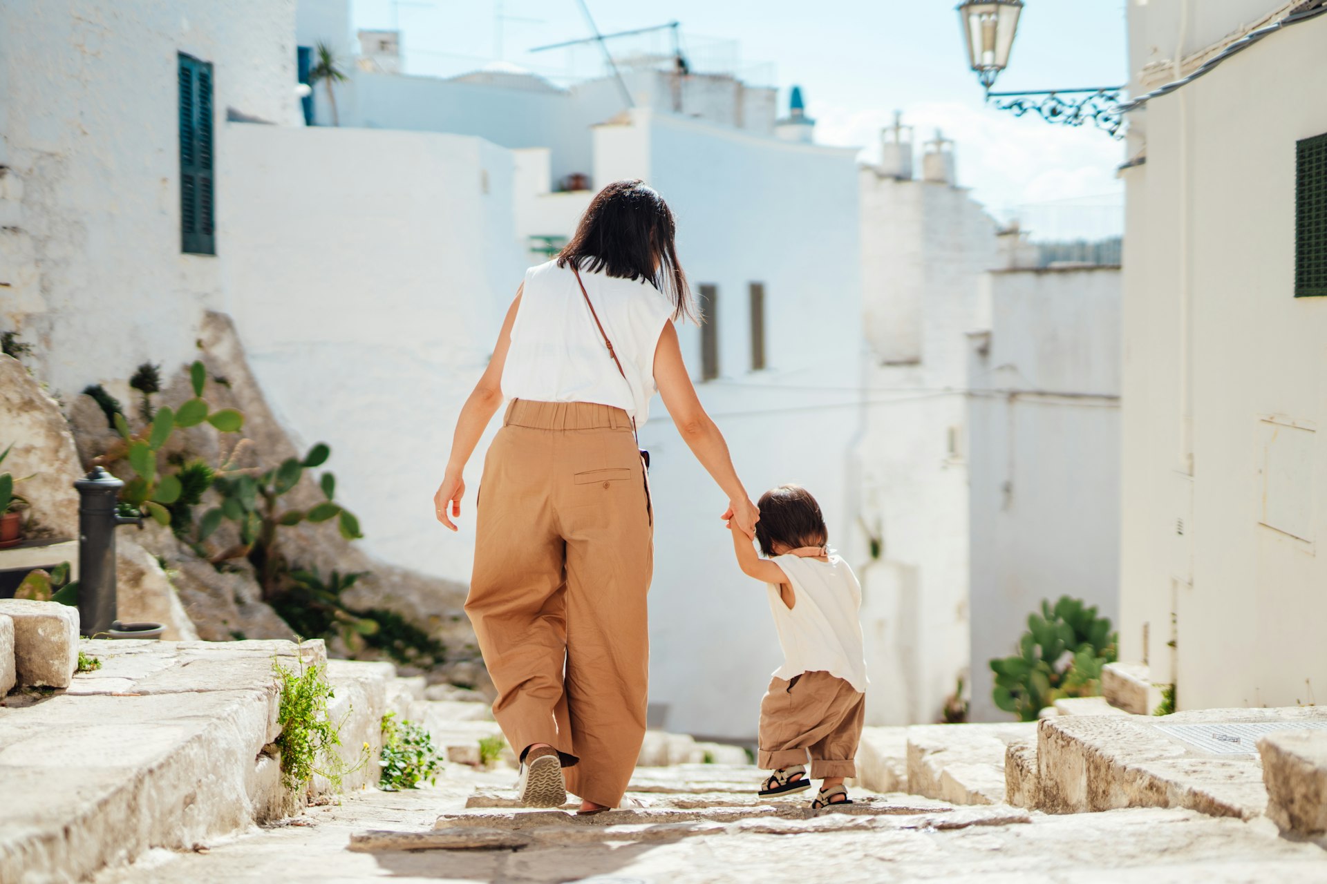 A mother and young child walk the narrow streets of Ostuni, Puglia, Italy