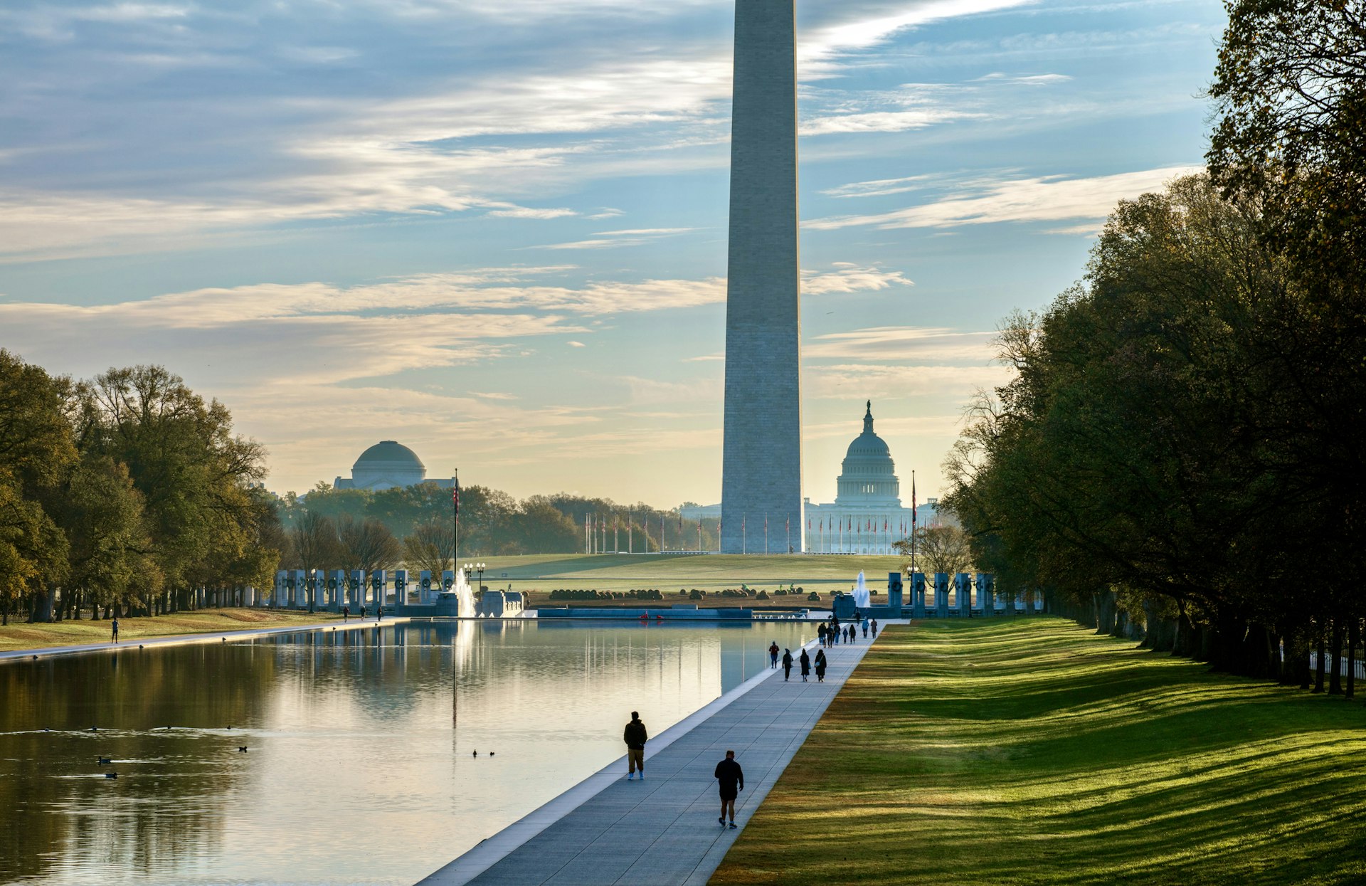 Sunrise over a rectangular body of water at the foot of a large monument