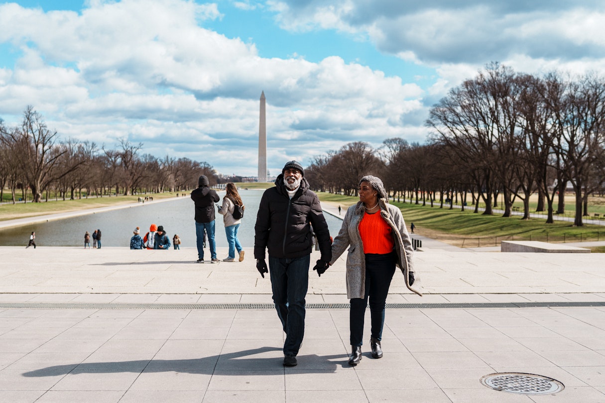 USA-Washington-DC-Fly View Productions-GettyImages-2052274111-RF Black senior couple exploring the Washington Mall while visiting Washington DC. A vibrant senior couple walk hand in hand while touring Washington DC on a fun and relaxing winter vacation, with the Lincoln Memorial Reflecting Pool and Washington Monument visible in the background. © Fly View Productions / Getty Images