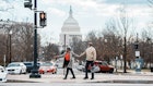 A vibrant senior couple of African American Descent hold hands and wait at a crosswalk while exploring Washington DC on a winter vacation, with a view of the United States Capitol visible in the background..2052274115
2052274115
Adult,  Bag,  Car,  Female,  Handbag,  Pedestrian,  Person,  Shoe,  Traffic Light,  Vehicle,  Woman