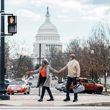 A vibrant senior couple of African American Descent hold hands and wait at a crosswalk while exploring Washington DC on a winter vacation, with a view of the United States Capitol visible in the background..2052274115
2052274115
Adult, Bag, Car, Female, Handbag, Pedestrian, Person, Shoe, Traffic Light, Vehicle, Woman