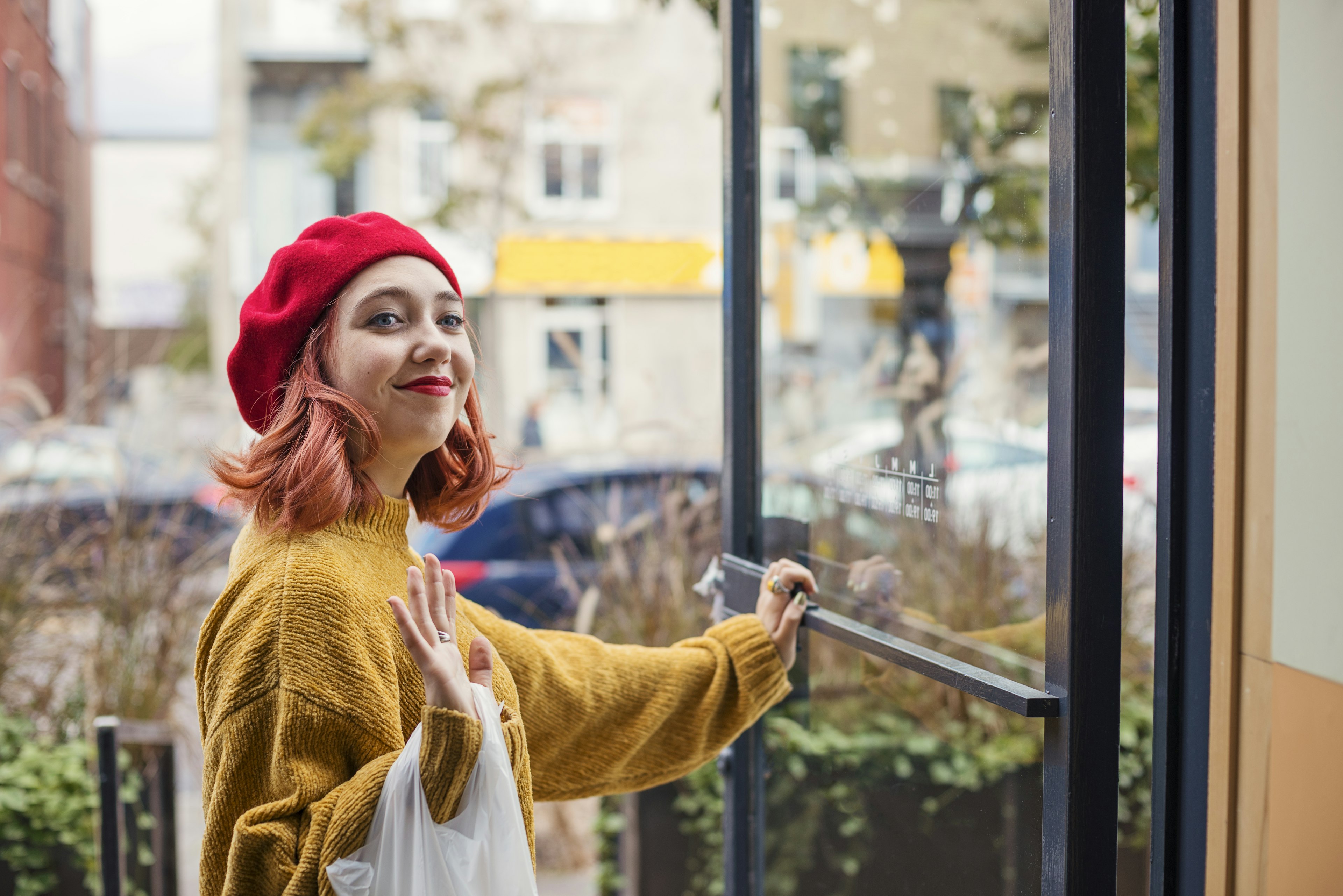 A woman in a red beret holds open a shop door, Montréal, Québec, Canada