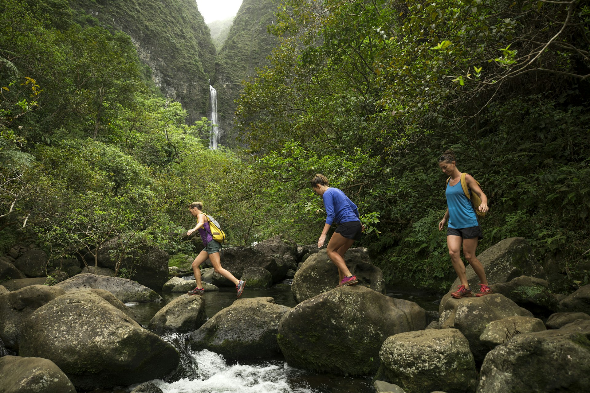 Three woman hiking in Hawaii with a big waterfall in the distance