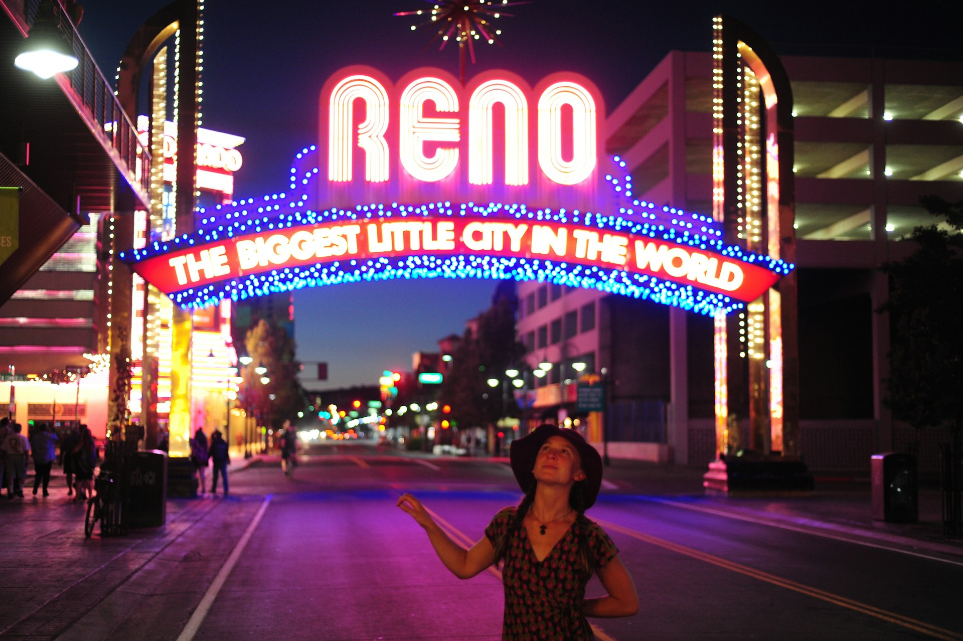 Woman looks up at the neon lights under illuminated archway sign, Commercial Row, Reno, Nevada, USA