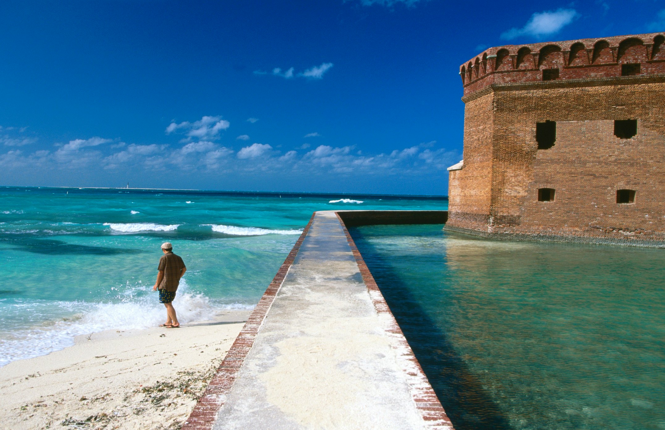 A man walks in the surf by the fort at Dry Tortugas National Parl, Florida.