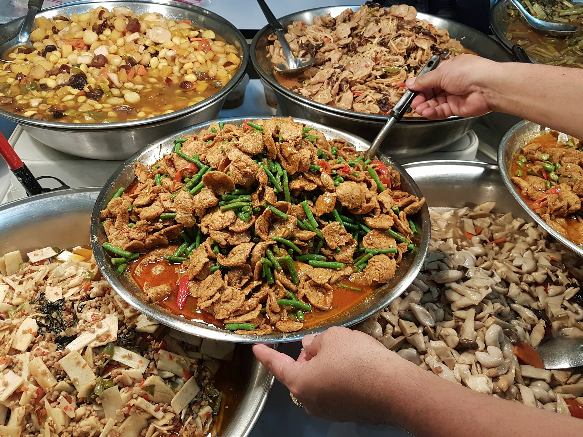A variety of Thai vegetarian curries and Thai food dishes being served in a market for the annual Thai Vegetarian Festival