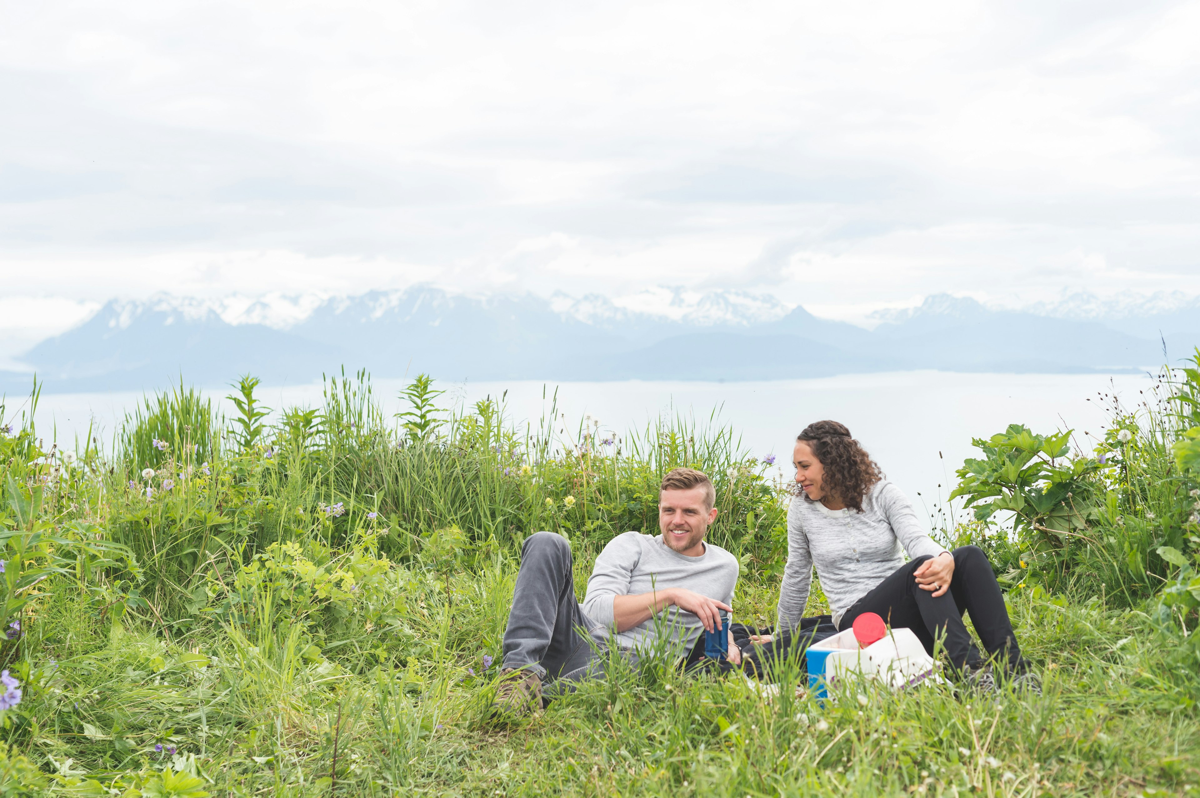 A couple enjoys a picnic with mountains in the distance, Alaska, USA