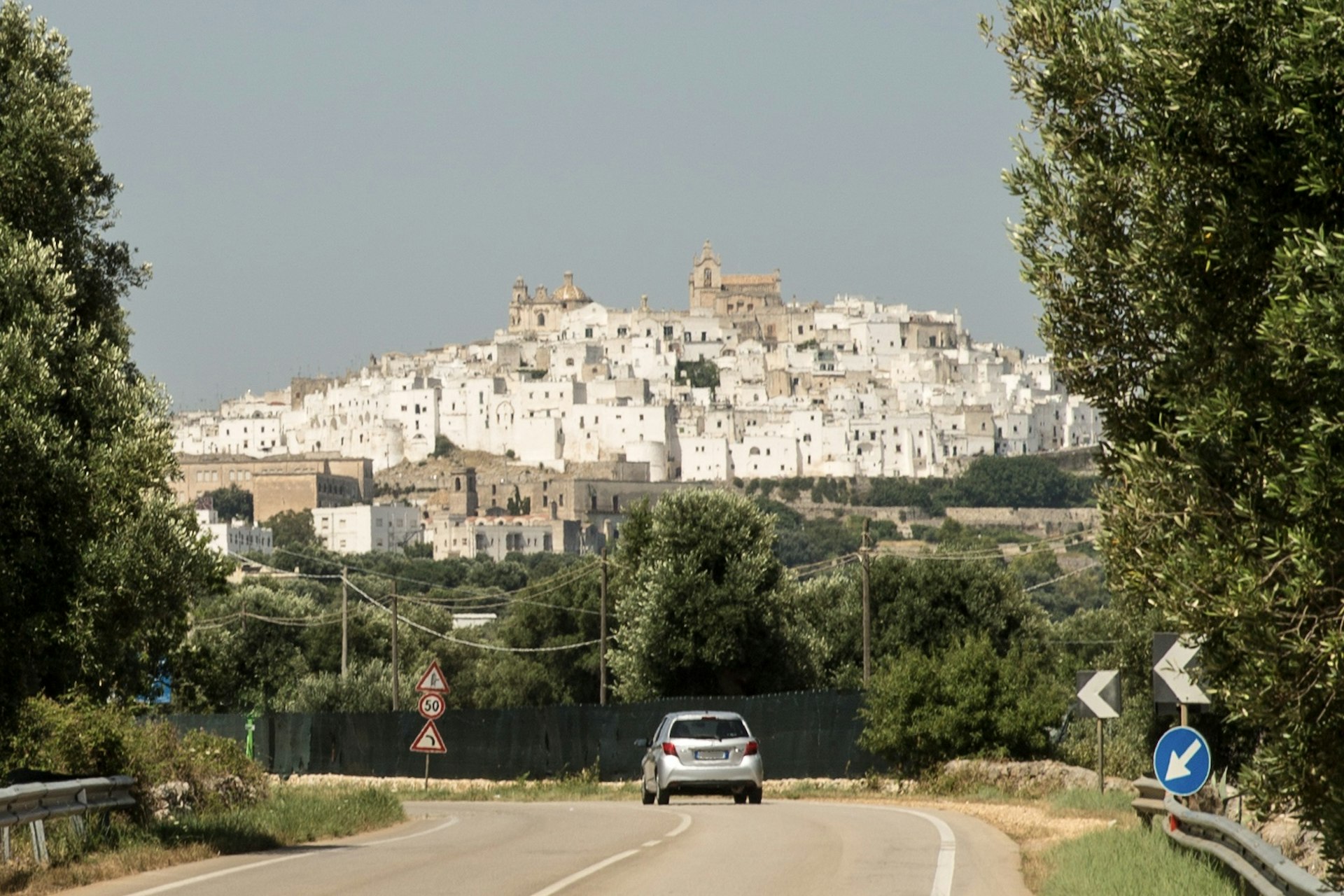 A car on a road with the hilltop town visible in the background, Ostini, Puglia, Italy
