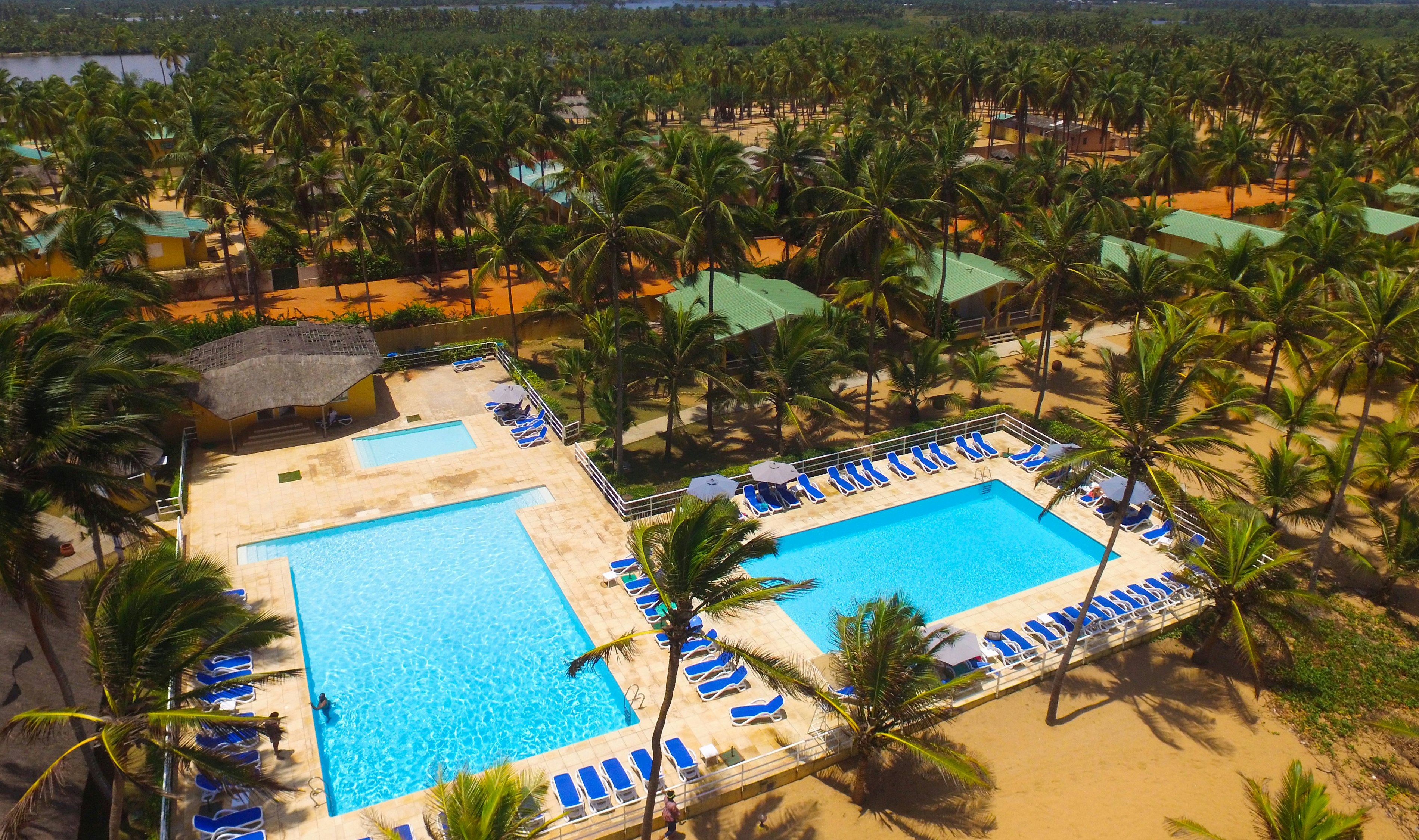 Two swimming pools surrounded by loungers and palm trees