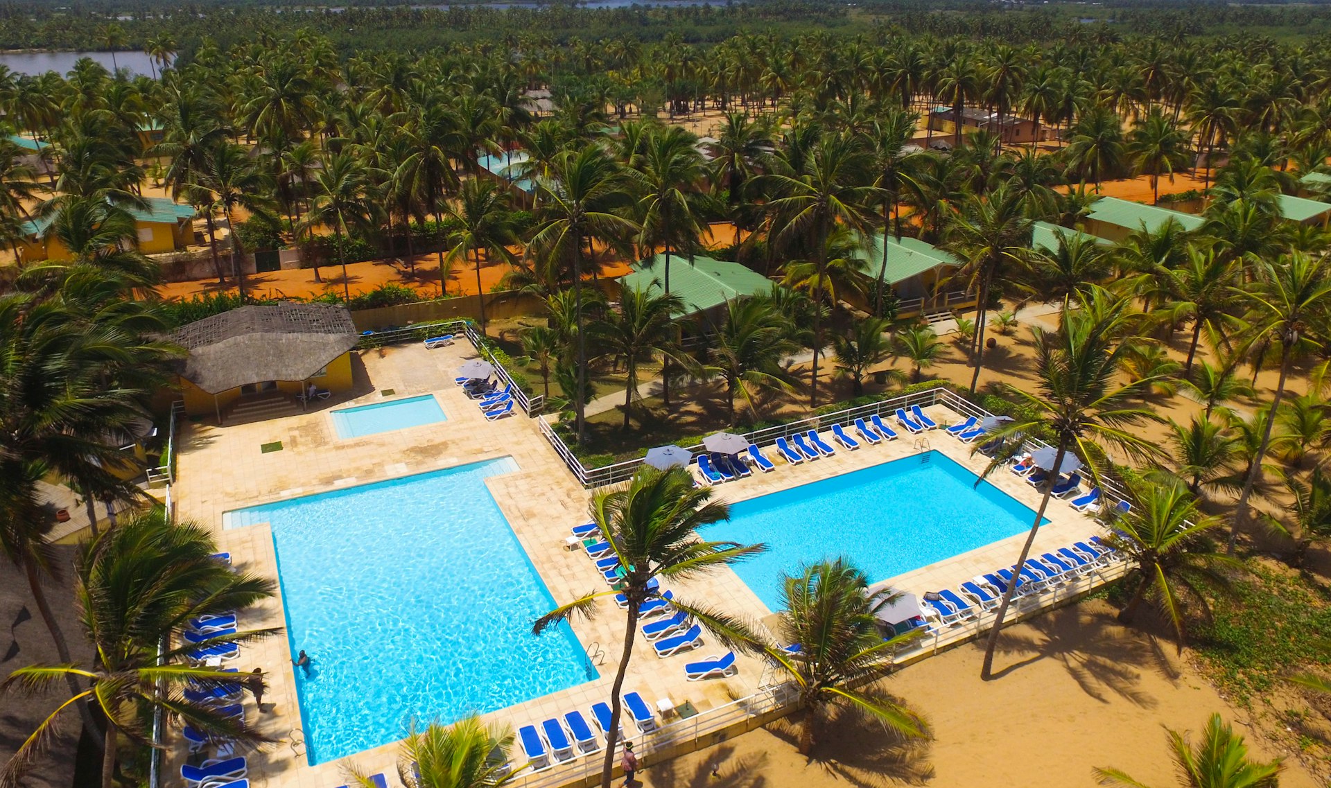 Two swimming pools surrounded by loungers and palm trees