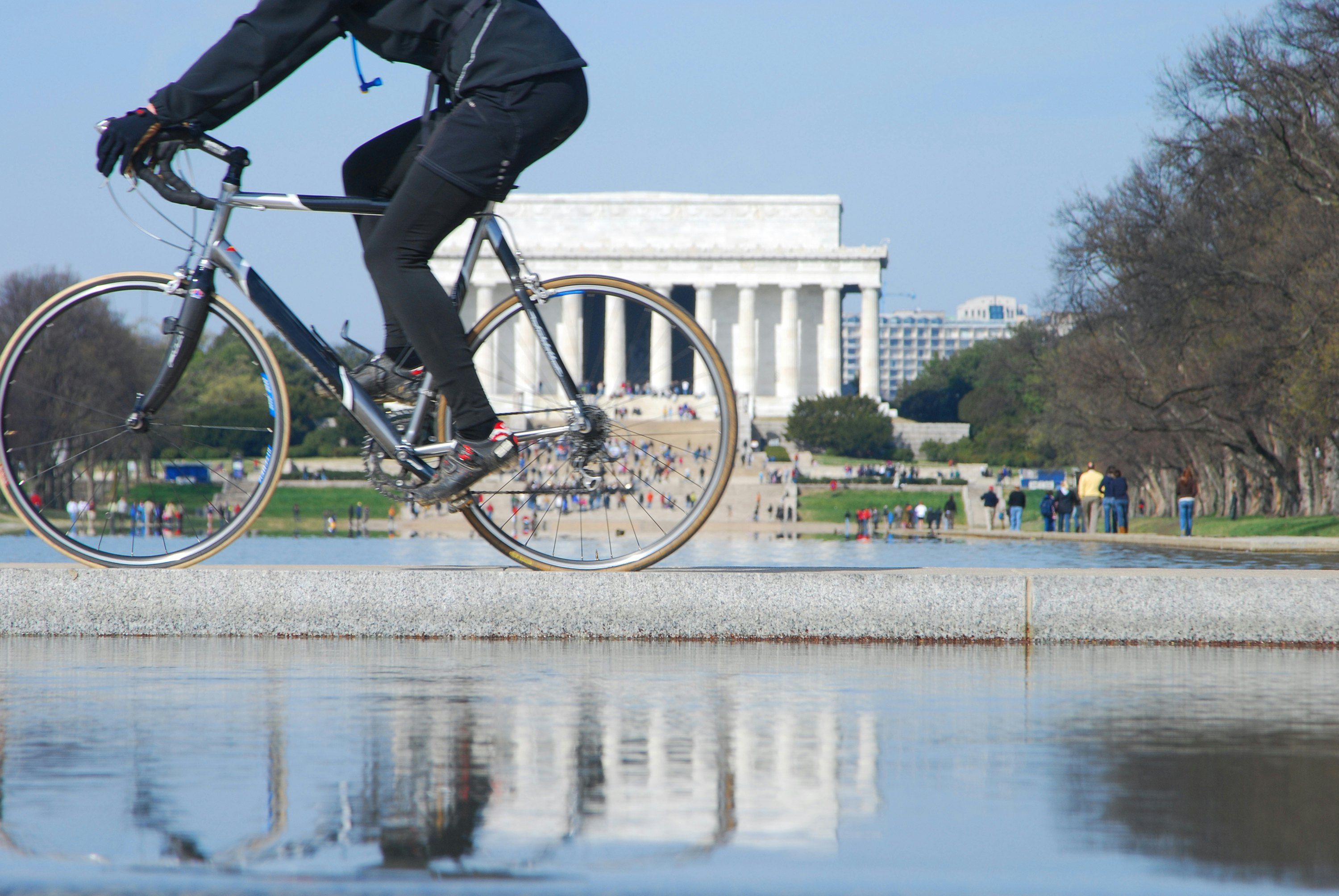 A cyclist pedals along in front of a distinctive white building