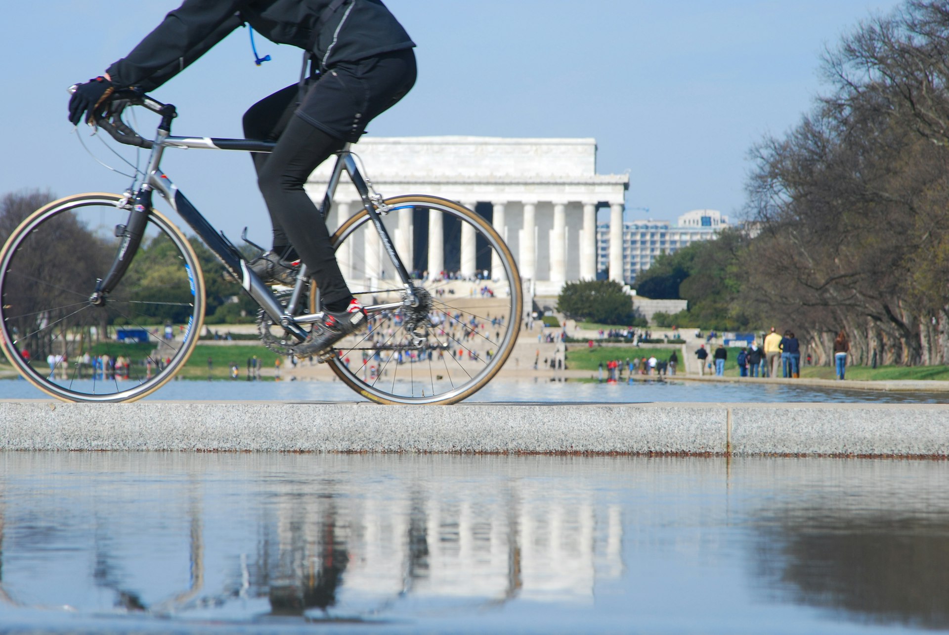A cyclist pedals along in front of a distinctive white building