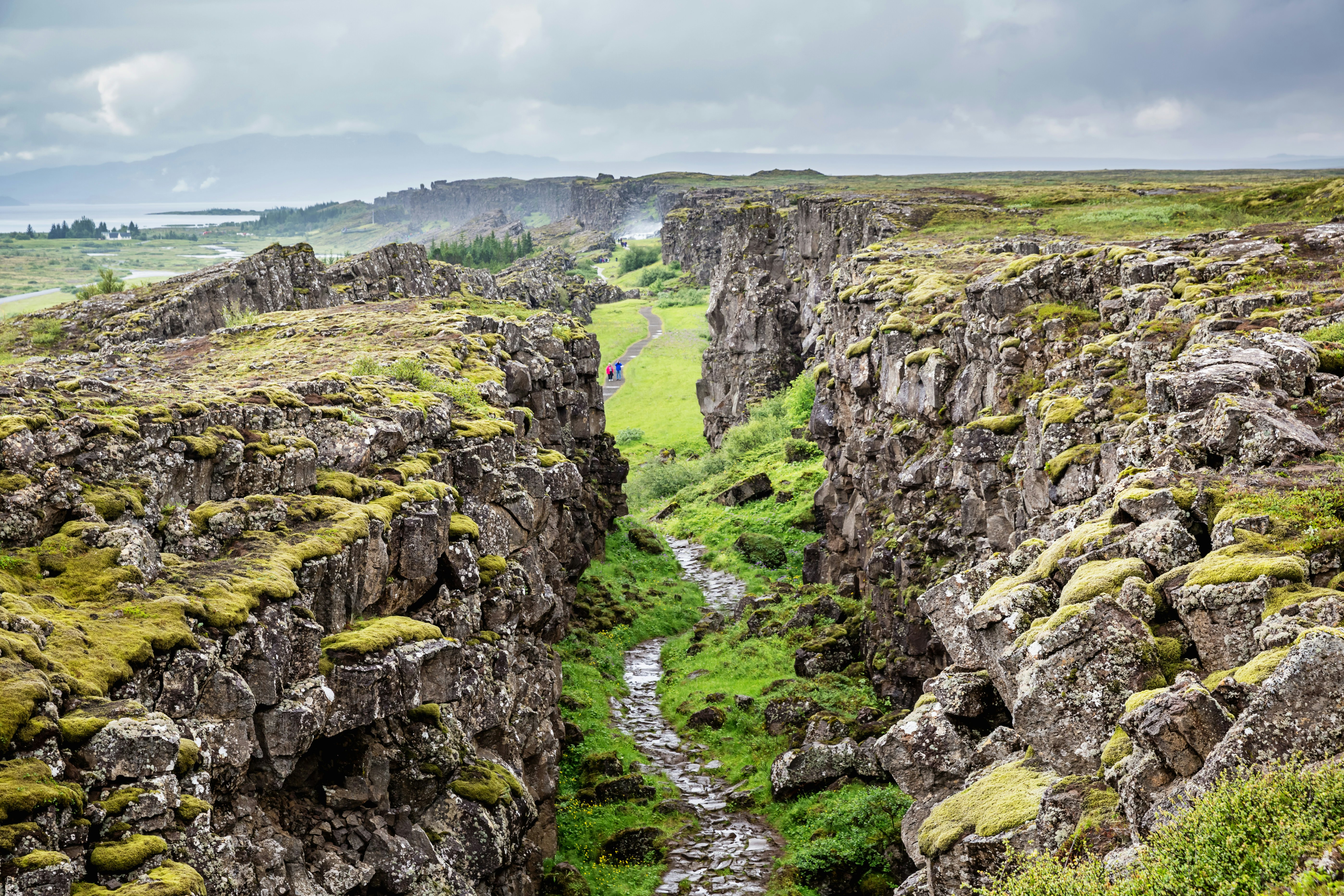 Walkers stroll along a path in between deep ravines and craggy rocks