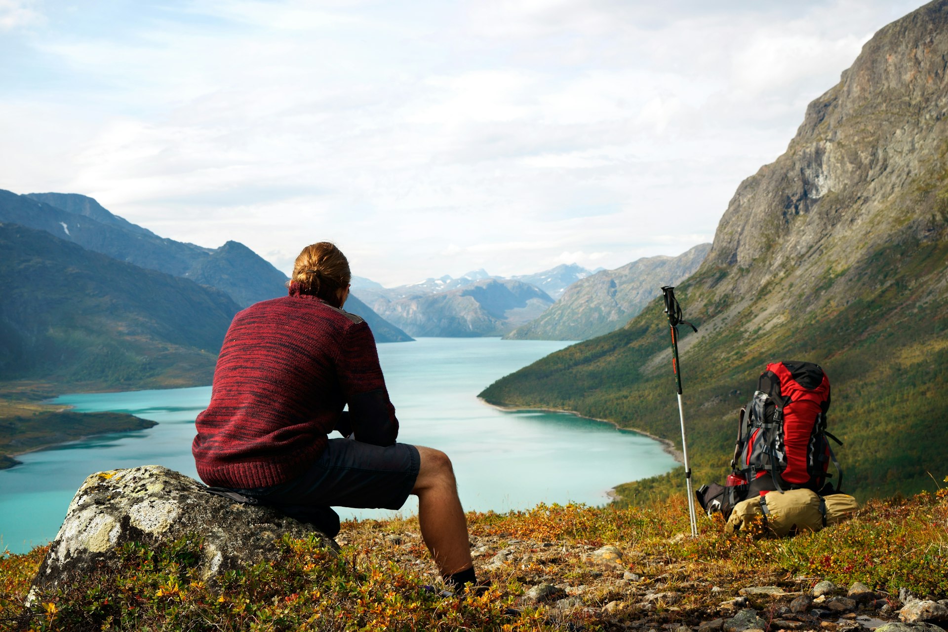 A hiker sits and pauses to look out over a stunning lake view
