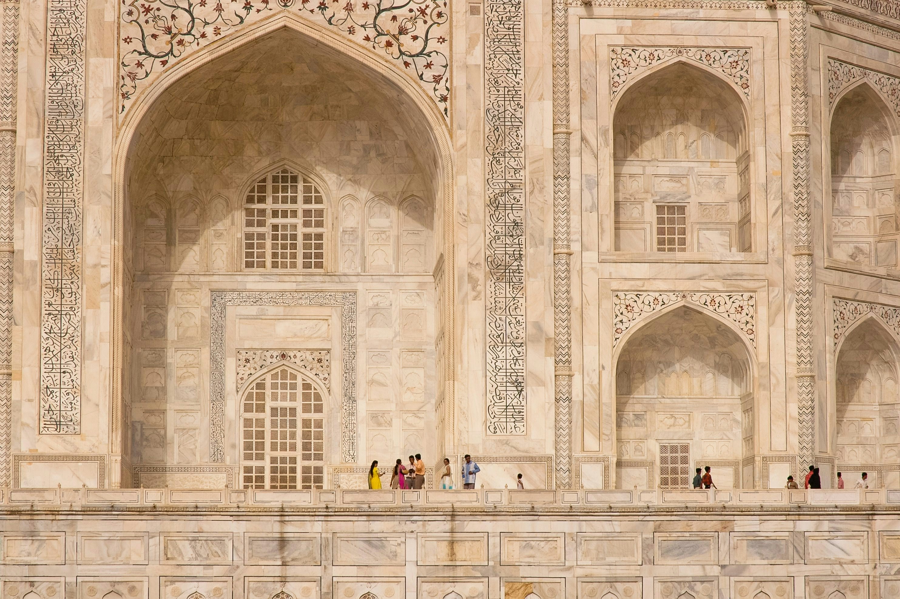 People in colourful clothes in front of the marble frontage of the Taj Mahal, Agra, India.