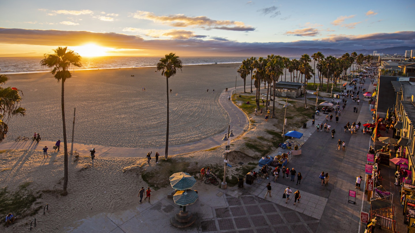 638340372
Adult; Adults Only; Beach; Beauty In Nature; Famous Place; Footpath; Men; Mixed Age Range; Recreational Pursuit; Sand; USA; Vacations; Venice - California; Venice Beach; Walking; Water; Women; California; High Angle View; Nature; Scenics - Nature; Sea; Sky; City Of Los Angeles; Cloud - Sky; Coastline; Horizon; Horizon Over Water; Horizontal; Orange Color; Outdoors; Pacific Ocean; Palm Tree; Pedestrian Walkway; People; Sun; Sunset; Tourism; Tourist; Curve; Landscape; Large Group Of People; Leisure Activity; Lifestyles; Photography; Travel;
High angle view of Venice beach during sunset. Tourists are walking on footpath by ocean. Shot of beautiful nature and people is taken from above.