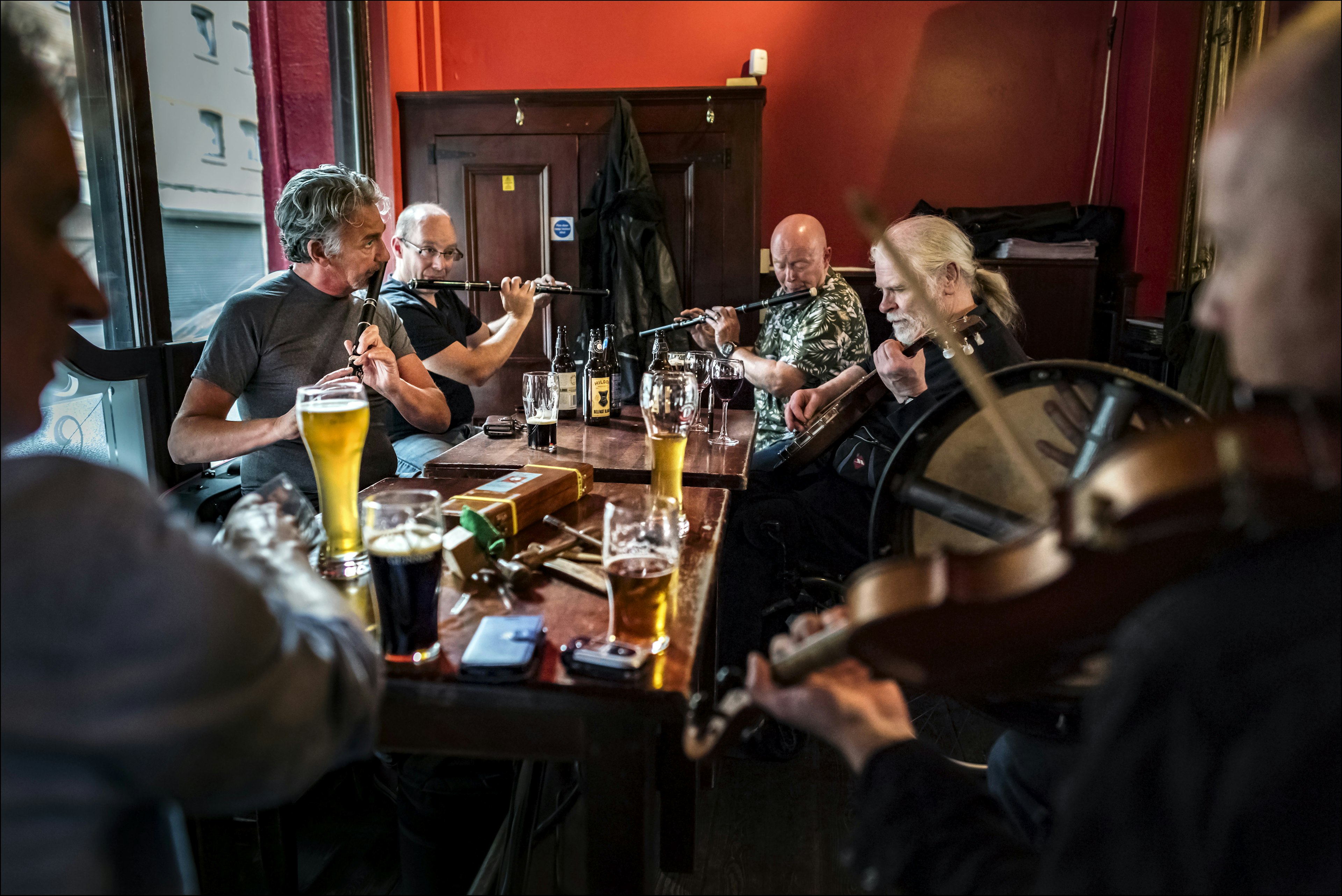 Irish musicians perform while seated on a table at the John Hewitt pub in Belfast.