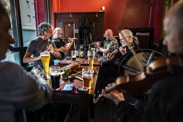 Irish musicians perform while seated on a table at the John Hewitt pub in Belfast.