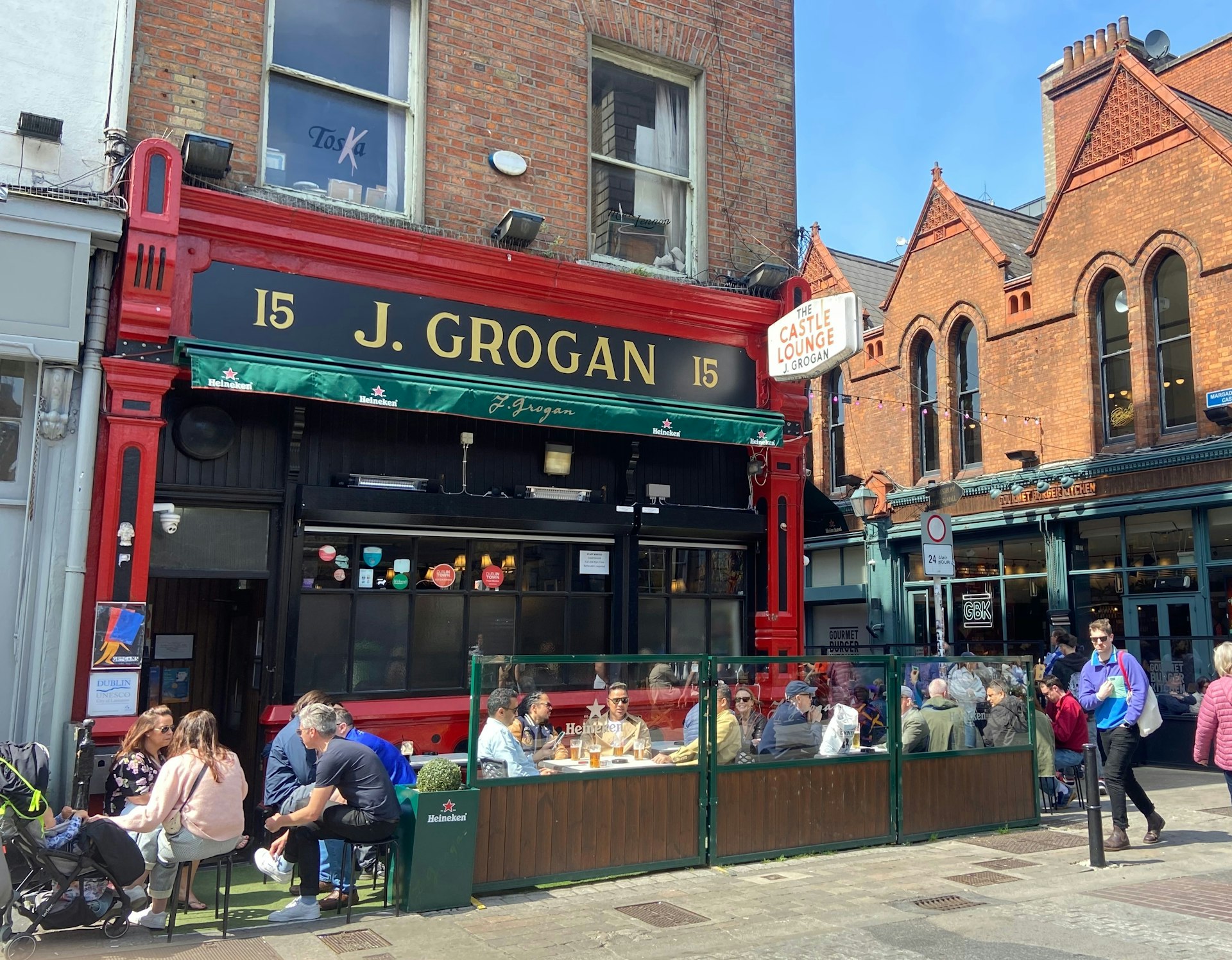 Exterior of Grogans pub in Dublin with people gathered on the sunny front terrace
