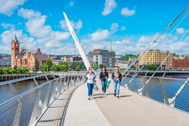 Young women cross the Peace Bridge in Derry, Northern Ireland