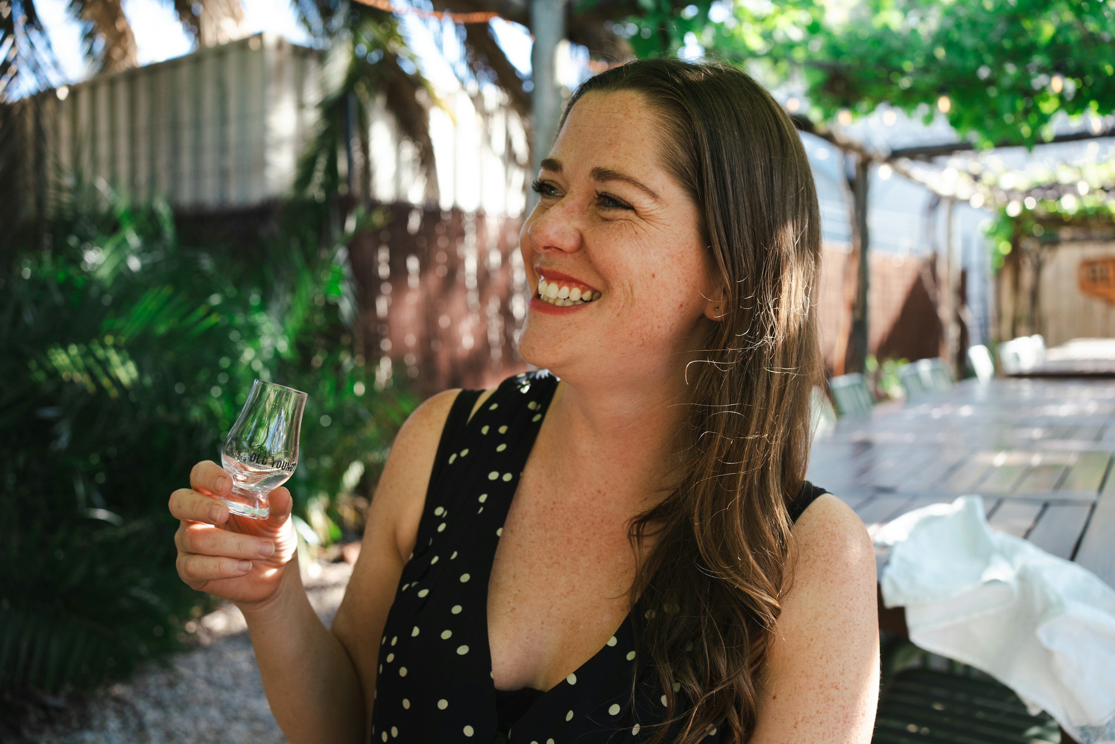 A beaming young woman samples gin at Old Young's Distillery