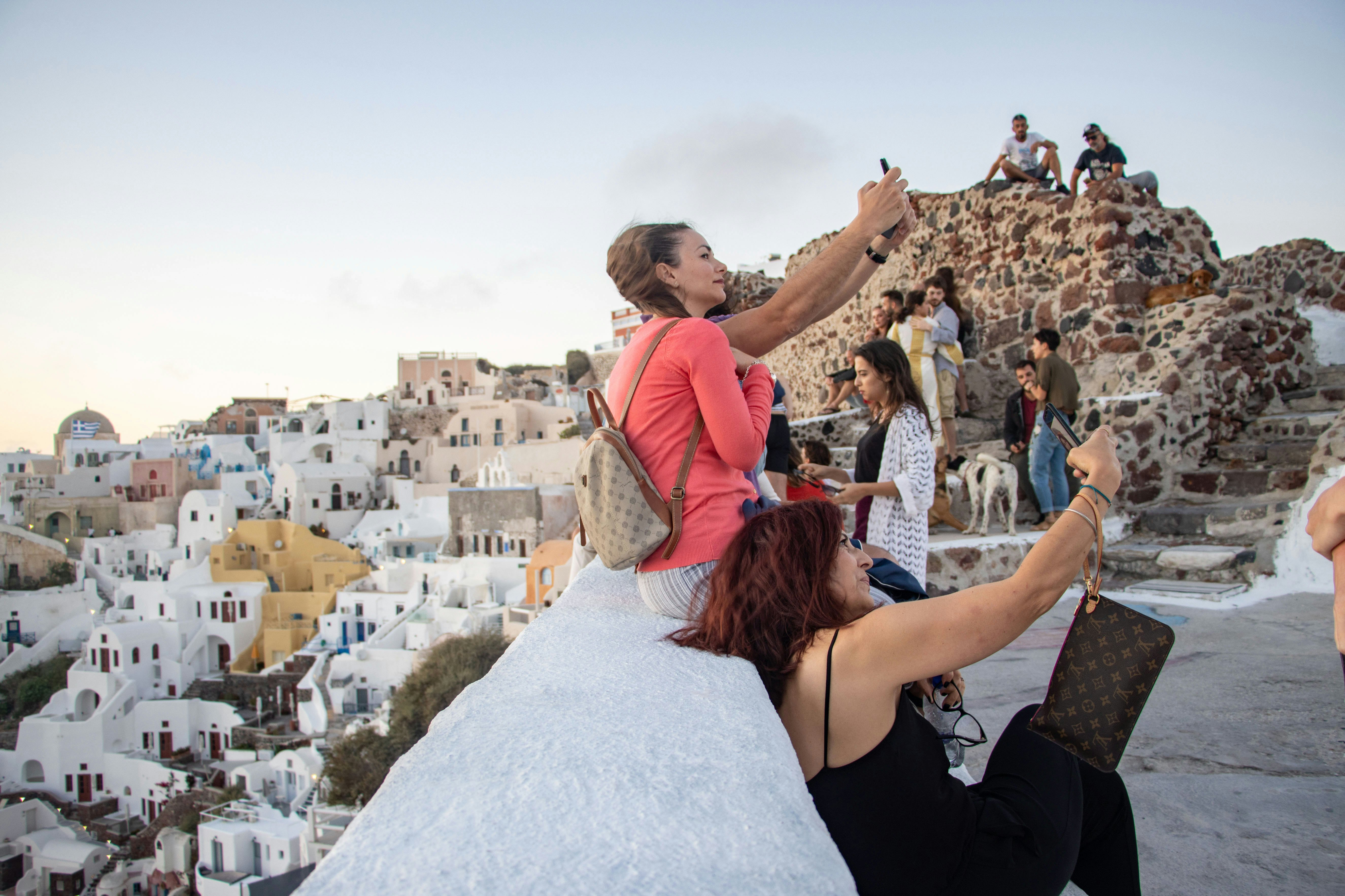 Tourists enjoying the amazing sunset at Oia in Santorini Volcano Island, in Cyclades, Aegean Sea, in Greece