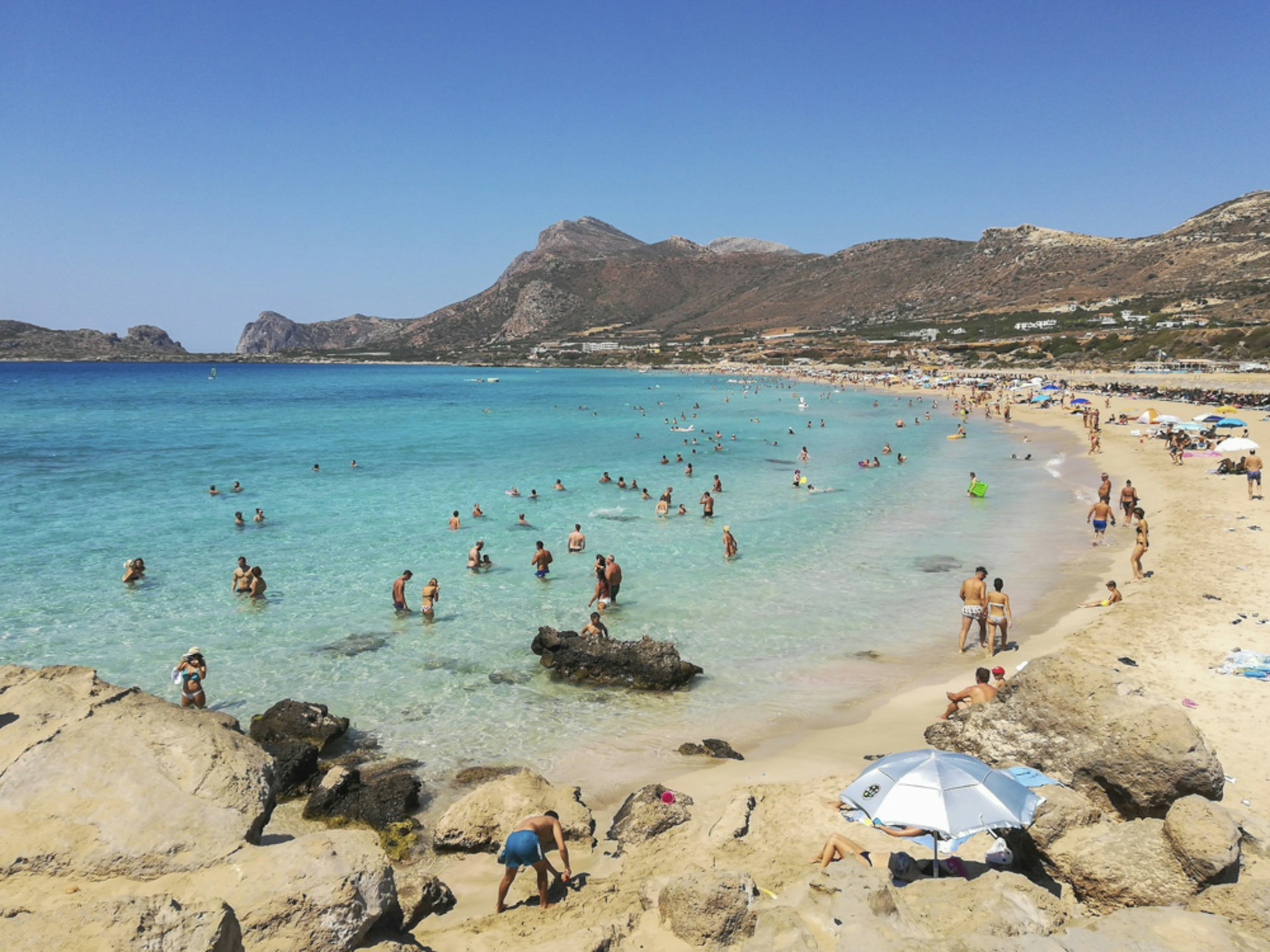 People enjoying a beach in Greece in the sunshine. 