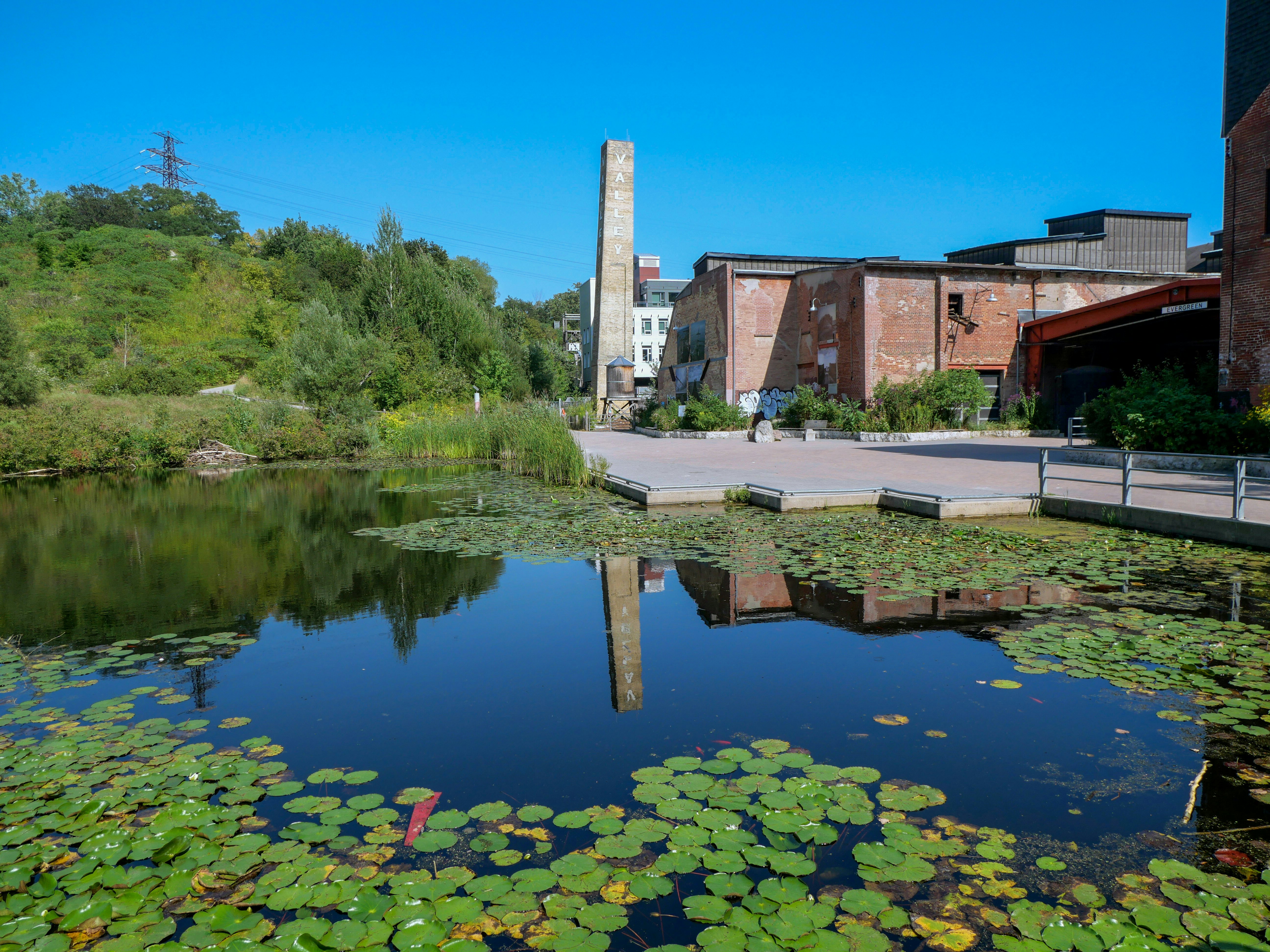 A red-brick chimney above an old factory near a pond