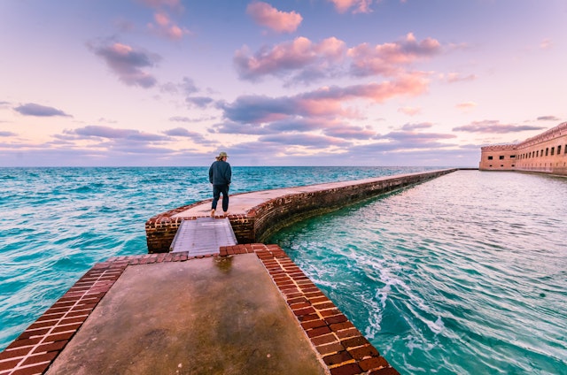 Man takes a morning walk on the moat around Port Jefferson at Dry Tortugas National Park, Florida Keys, Florida, USA